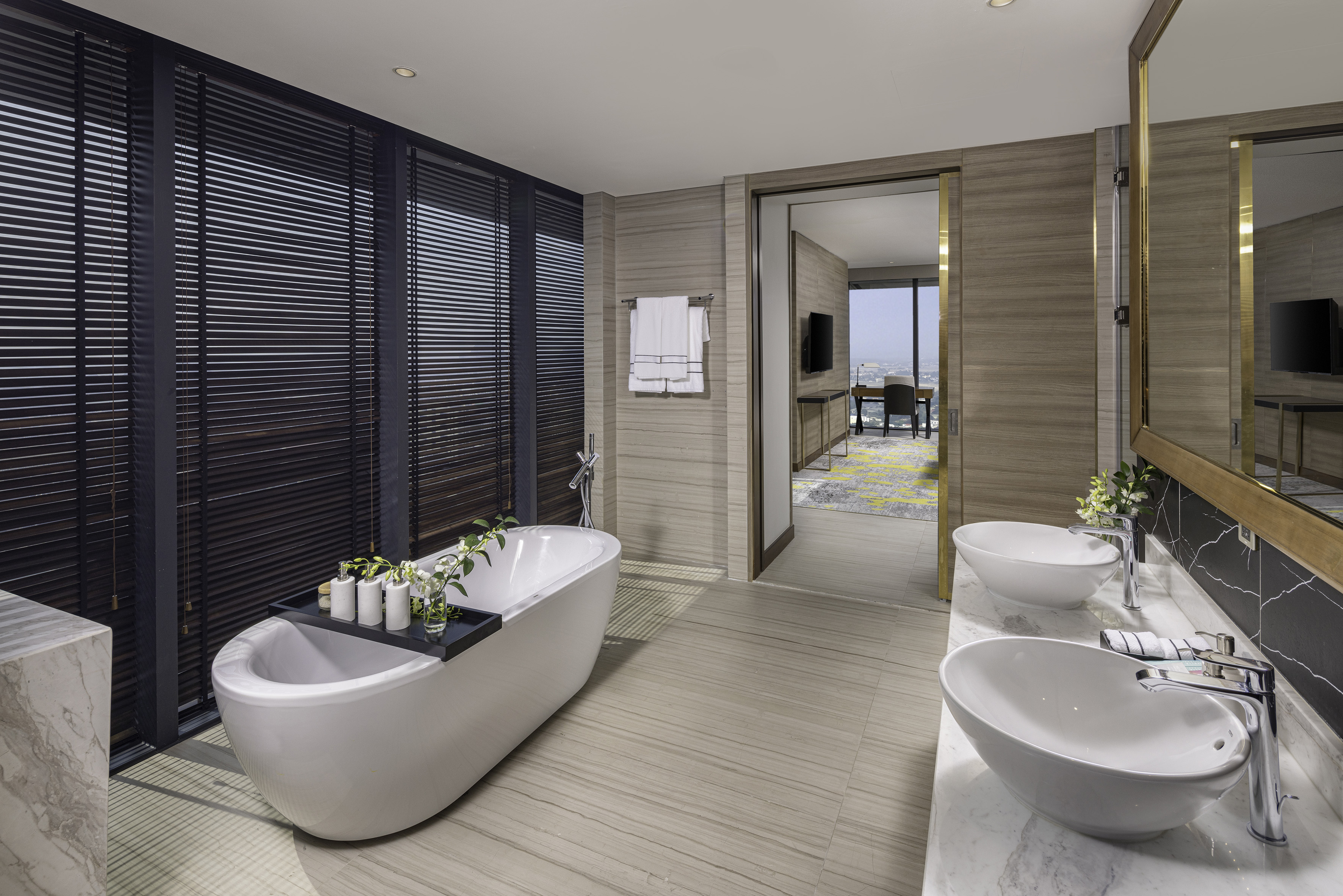 Modern luxury hotel bathroom with freestanding tub, double vanity, and city view.