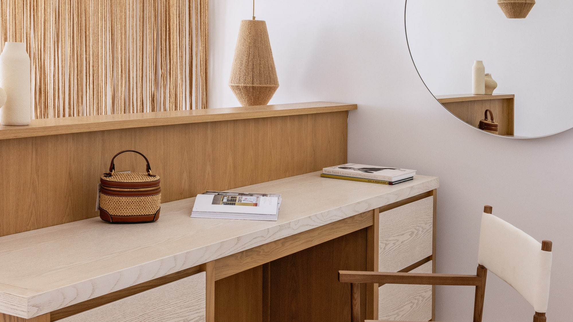 Modern wooden vanity, macrame wall art, woven pendant lights, and round mirror.