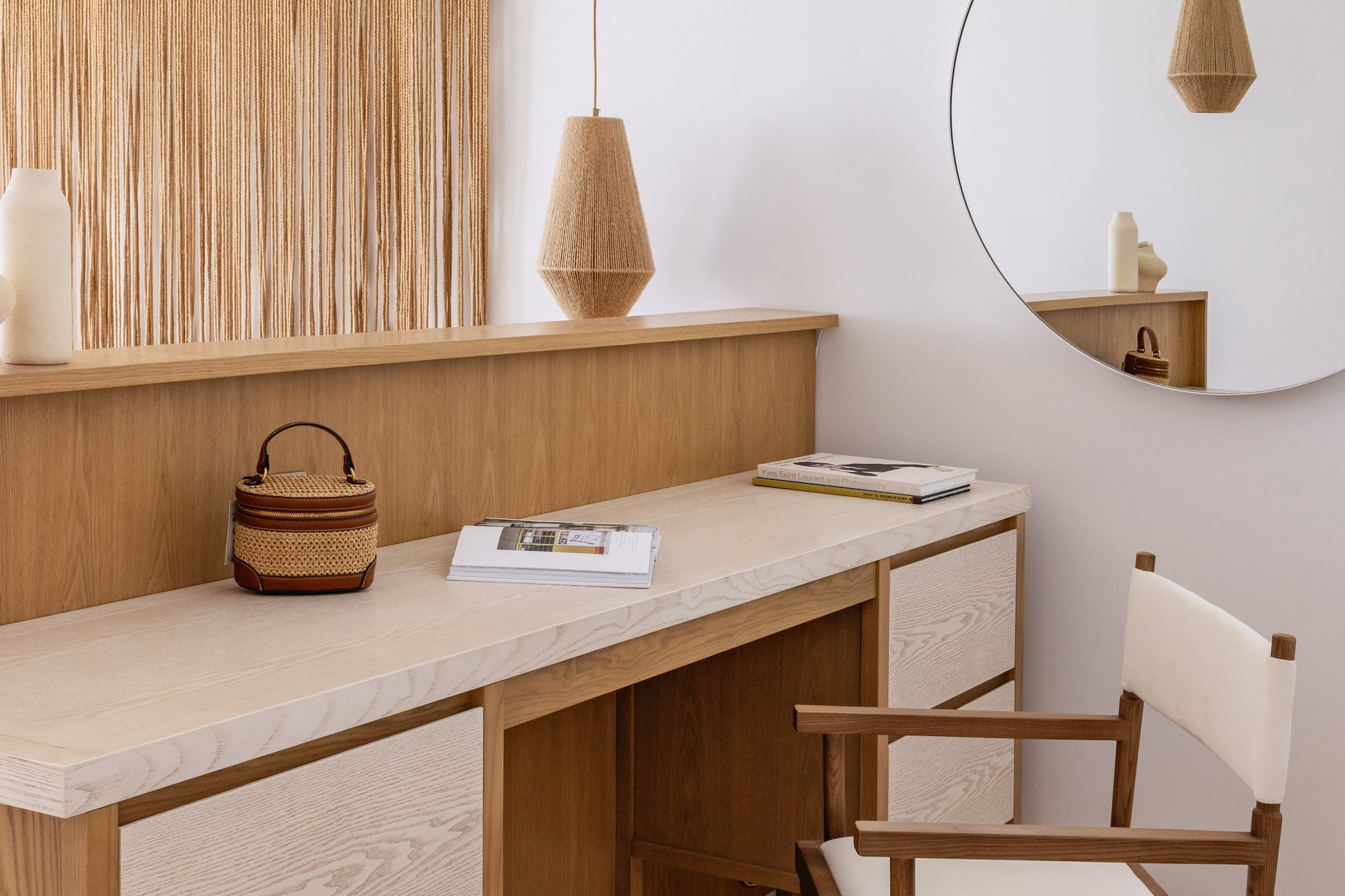 Modern wooden vanity, macrame wall art, woven pendant lights, and round mirror.