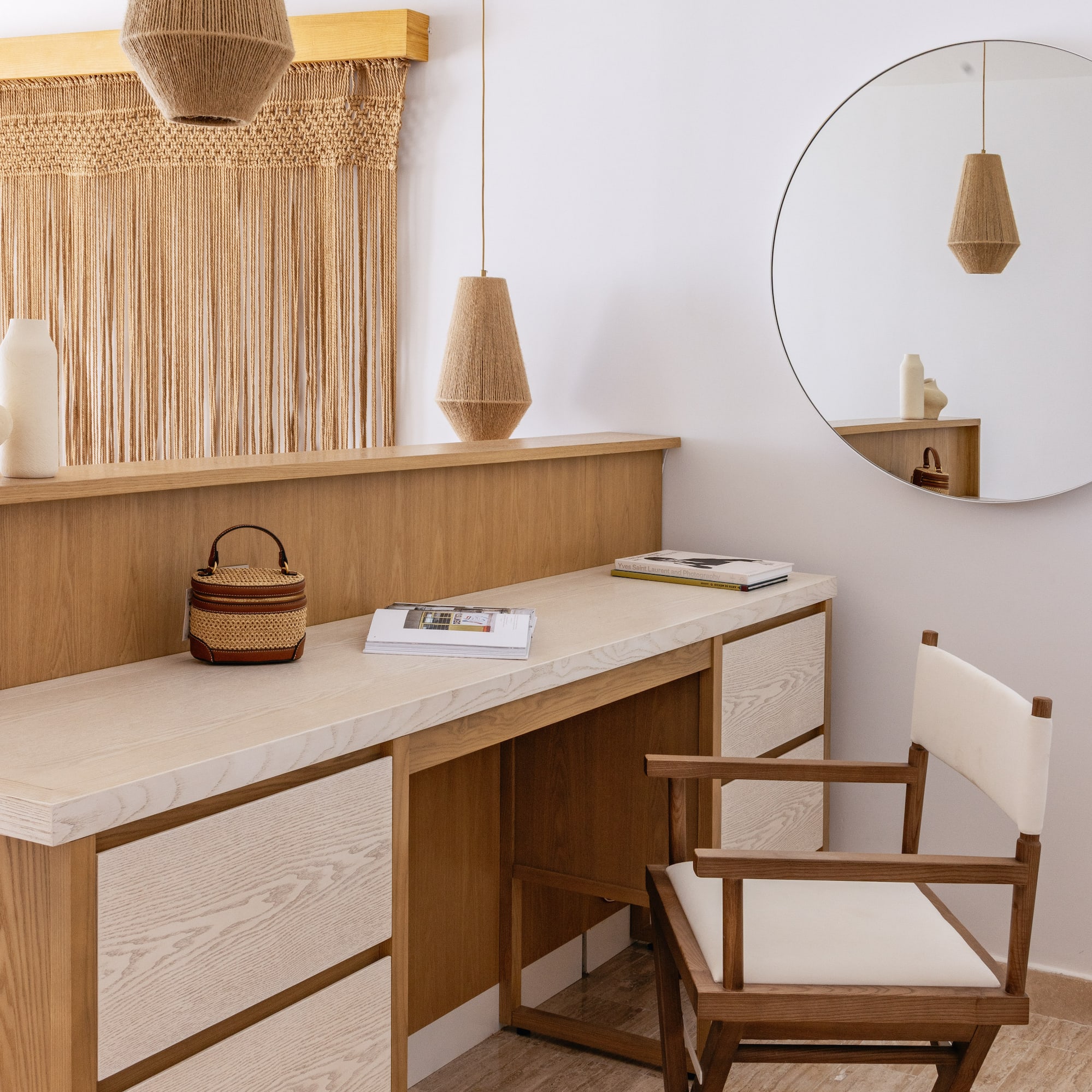 Modern wooden vanity, macrame wall art, woven pendant lights, and round mirror.