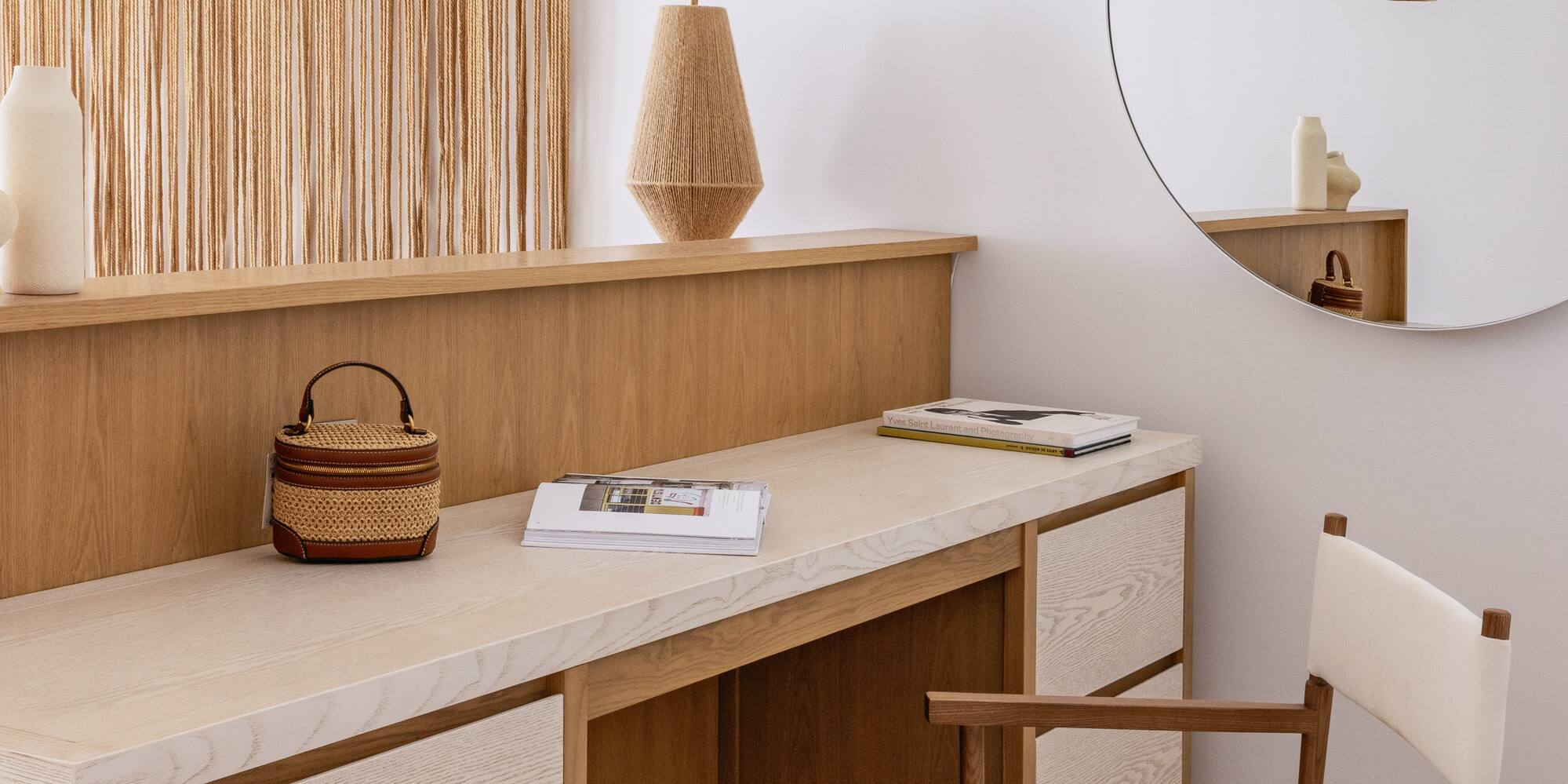 Modern wooden vanity, macrame wall art, woven pendant lights, and round mirror.