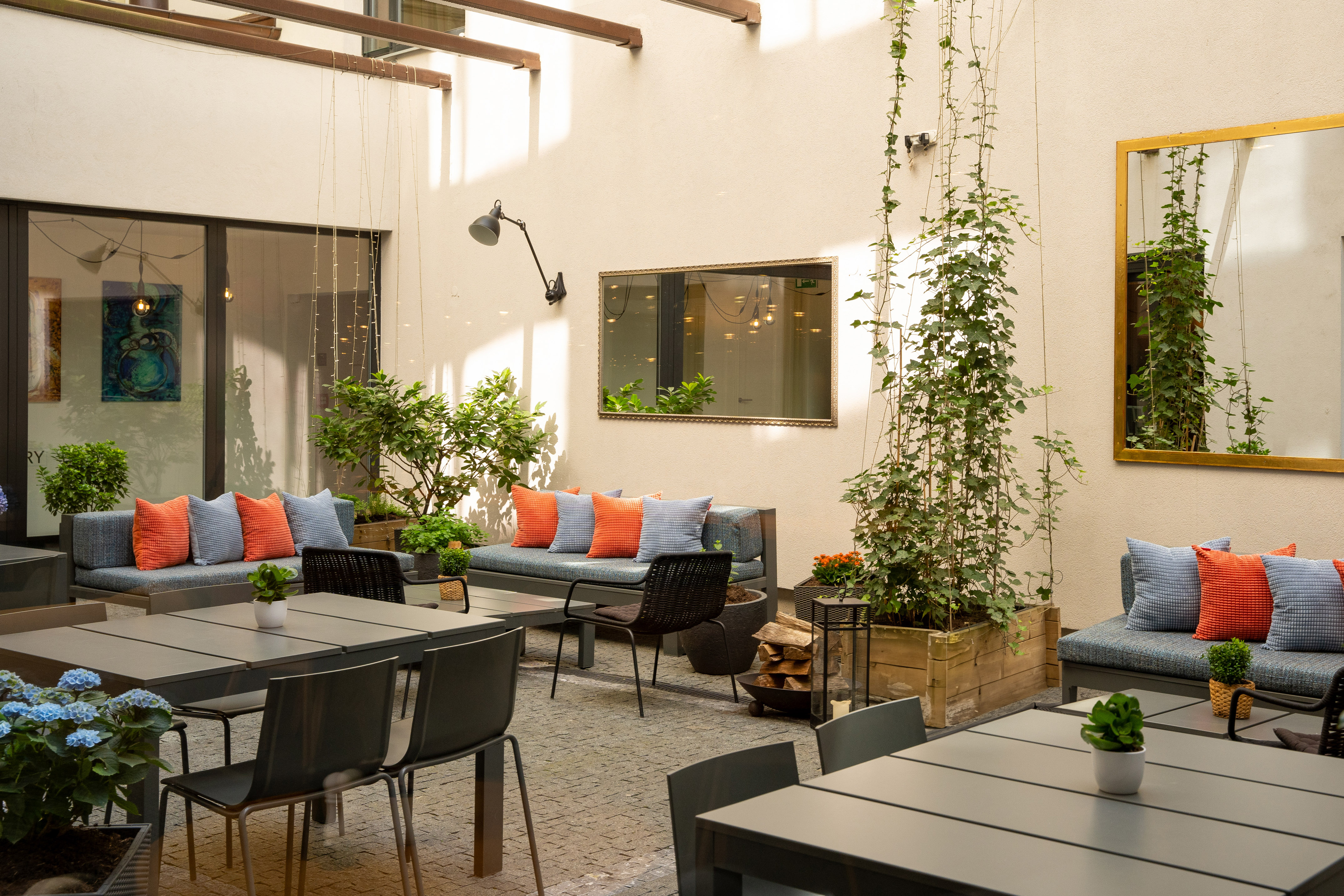 Modern courtyard patio with lounge seating, dining tables, and plants.