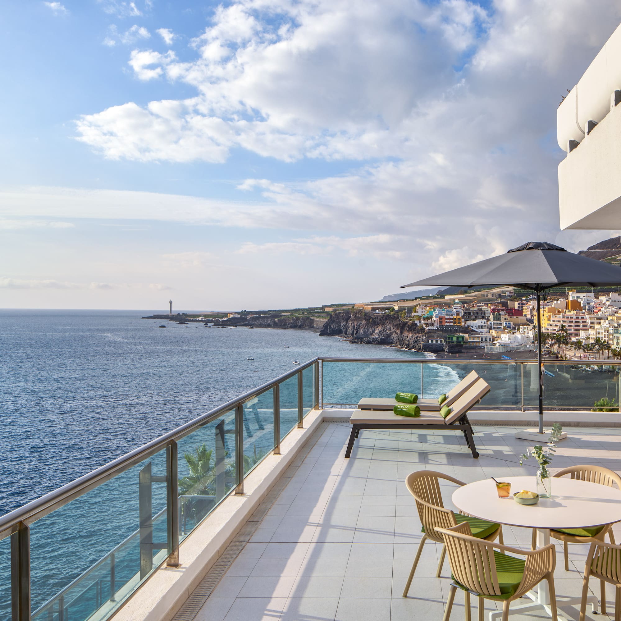 a patio with chairs and umbrella overlooking the ocean