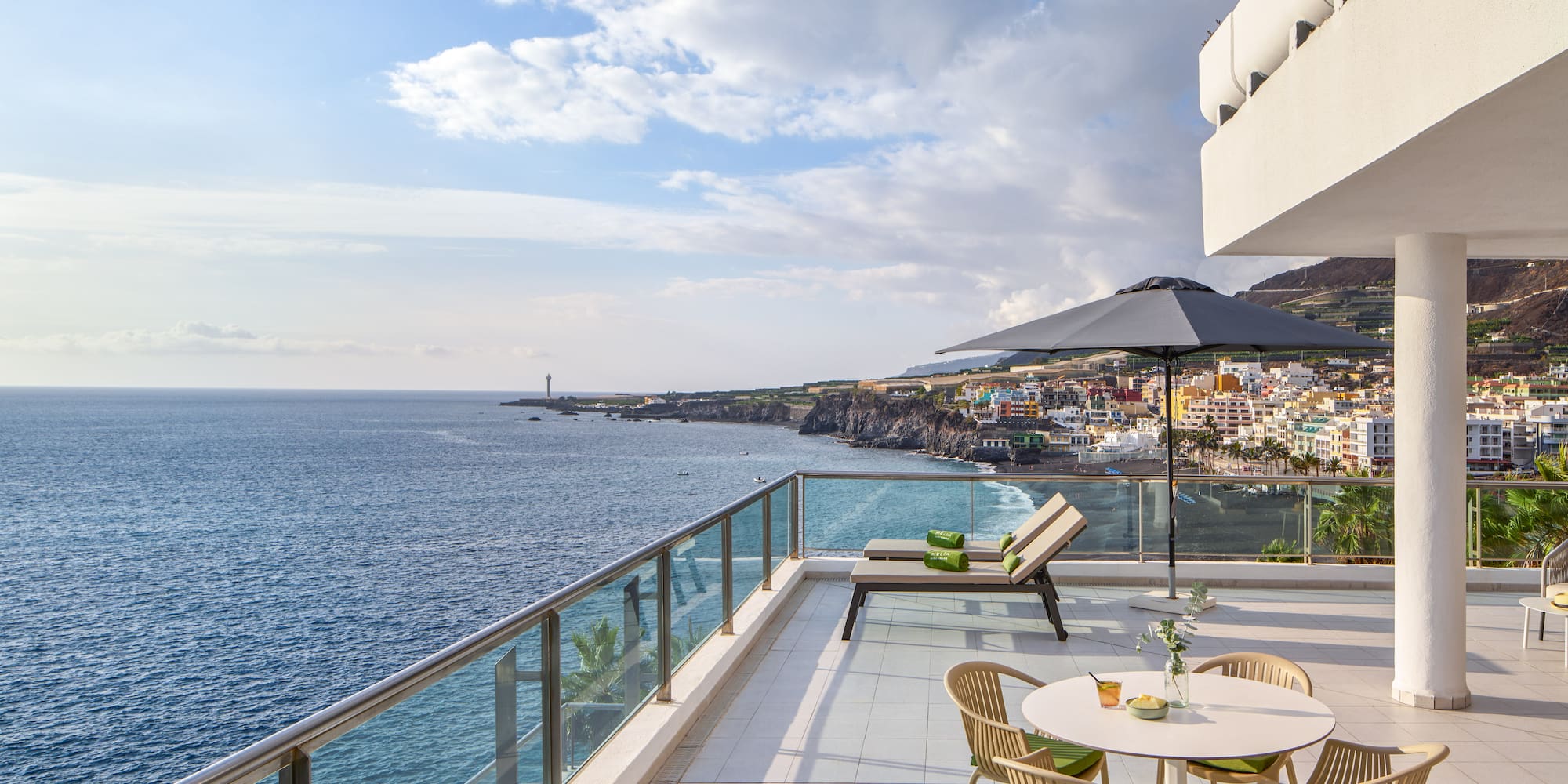 a patio with chairs and umbrella overlooking the ocean