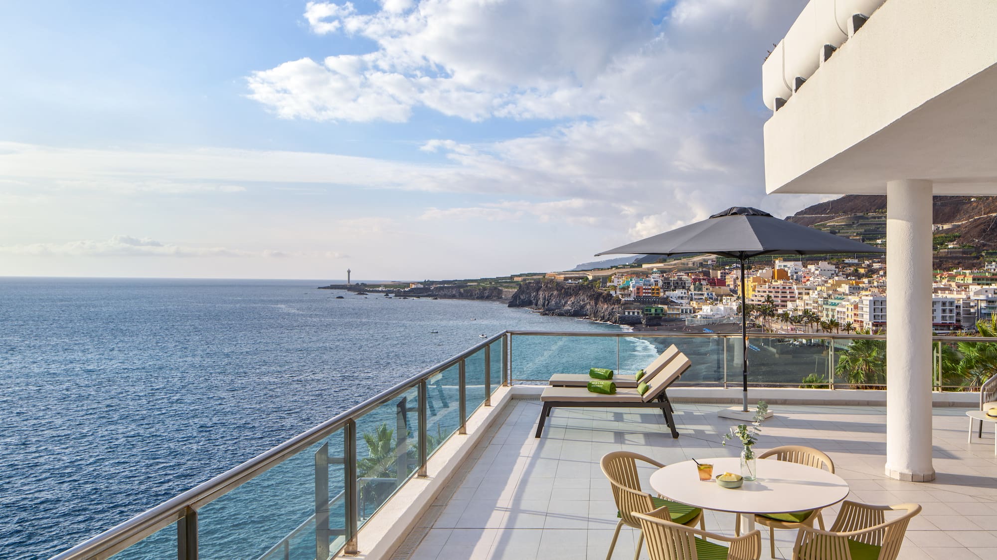 a patio with chairs and umbrella overlooking the ocean