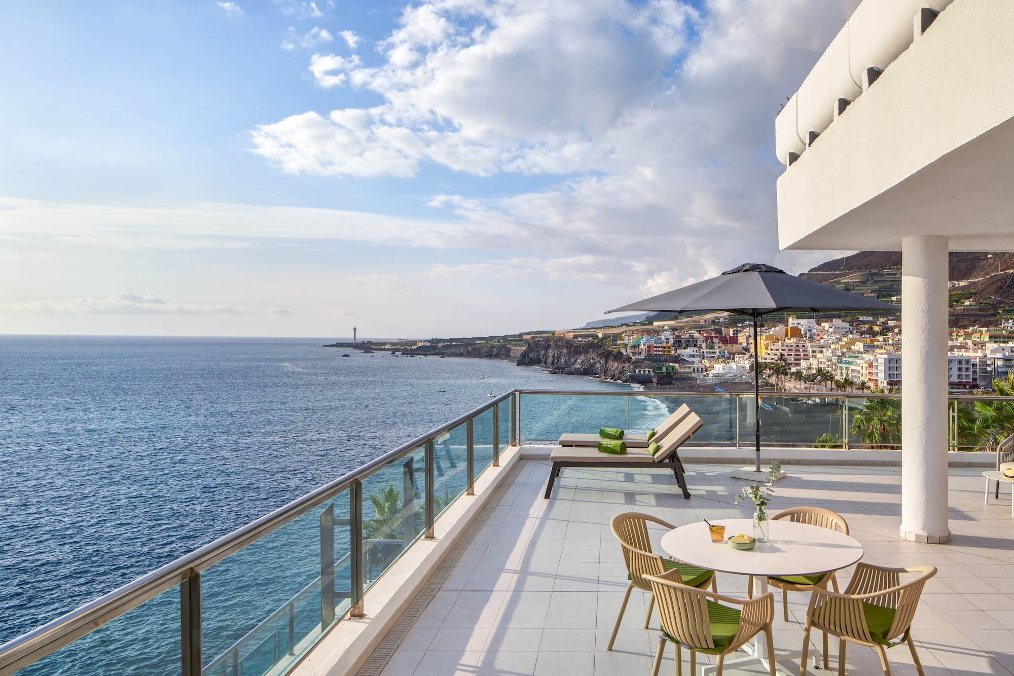 a patio with chairs and umbrella overlooking the ocean