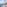 Sunny ocean view balcony with lounge chairs, coastal town, and lighthouse.