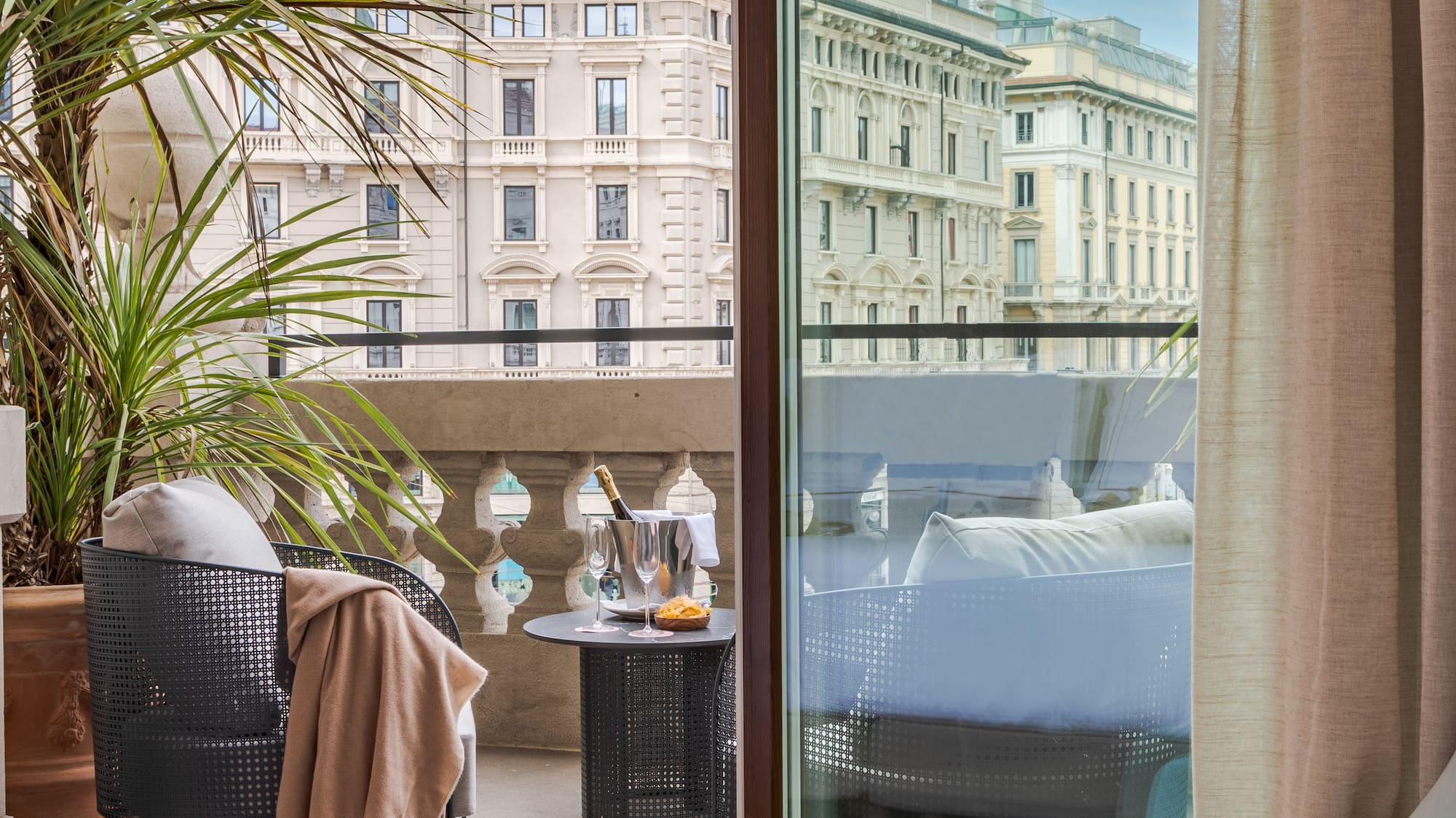a room with a glass door and a balcony with a plant and a window