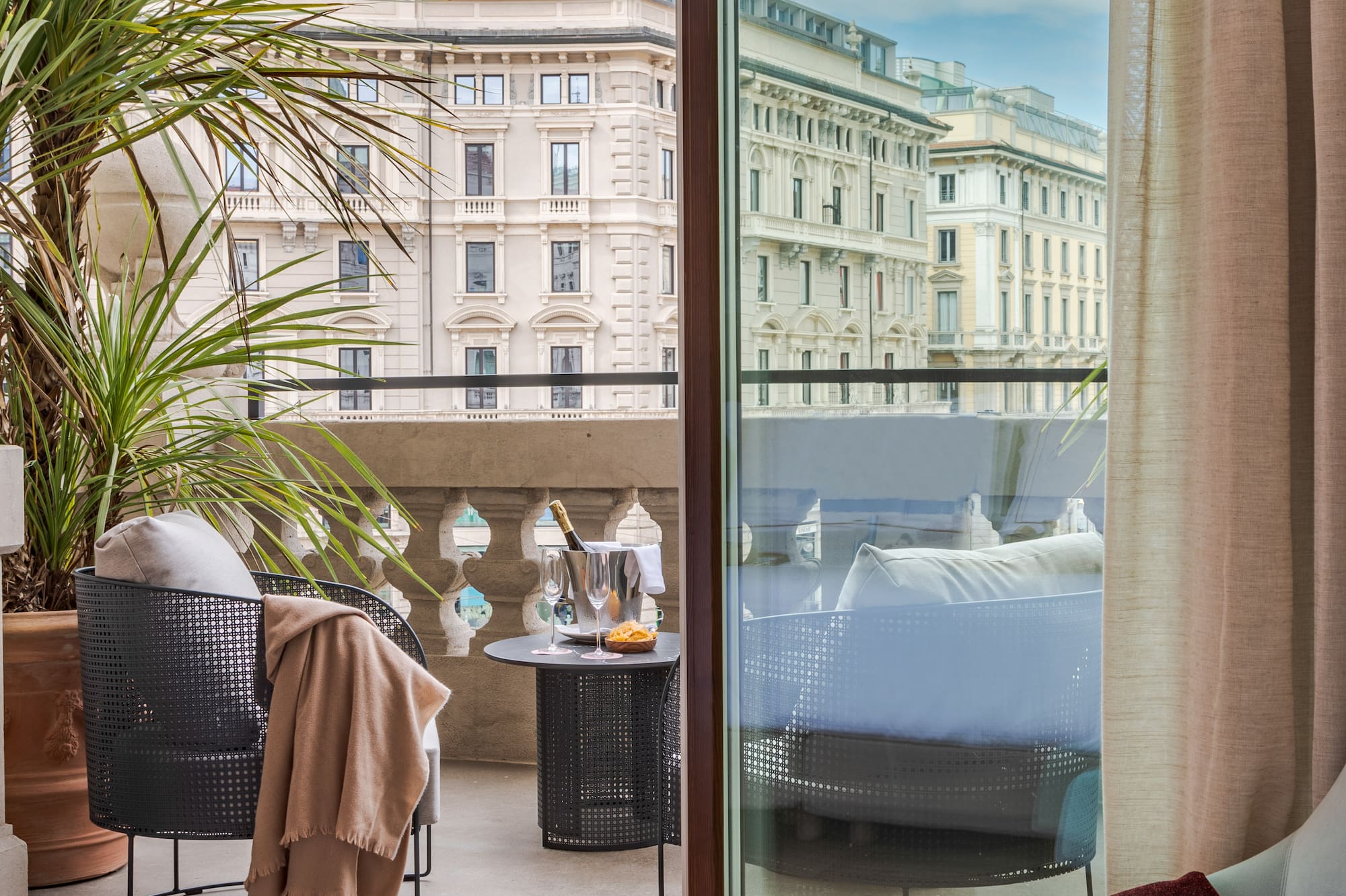 a room with a glass door and a balcony with a plant and a window