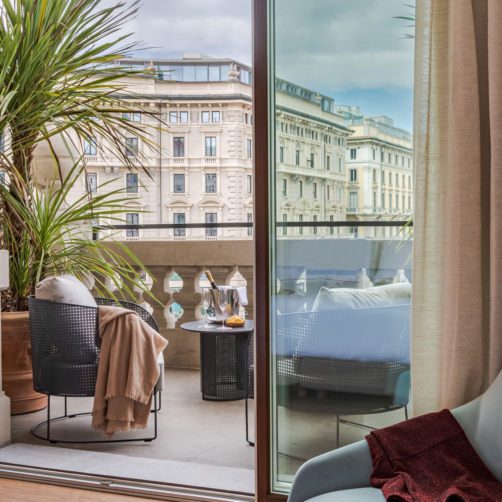 a room with a glass door and a balcony with a plant and a window