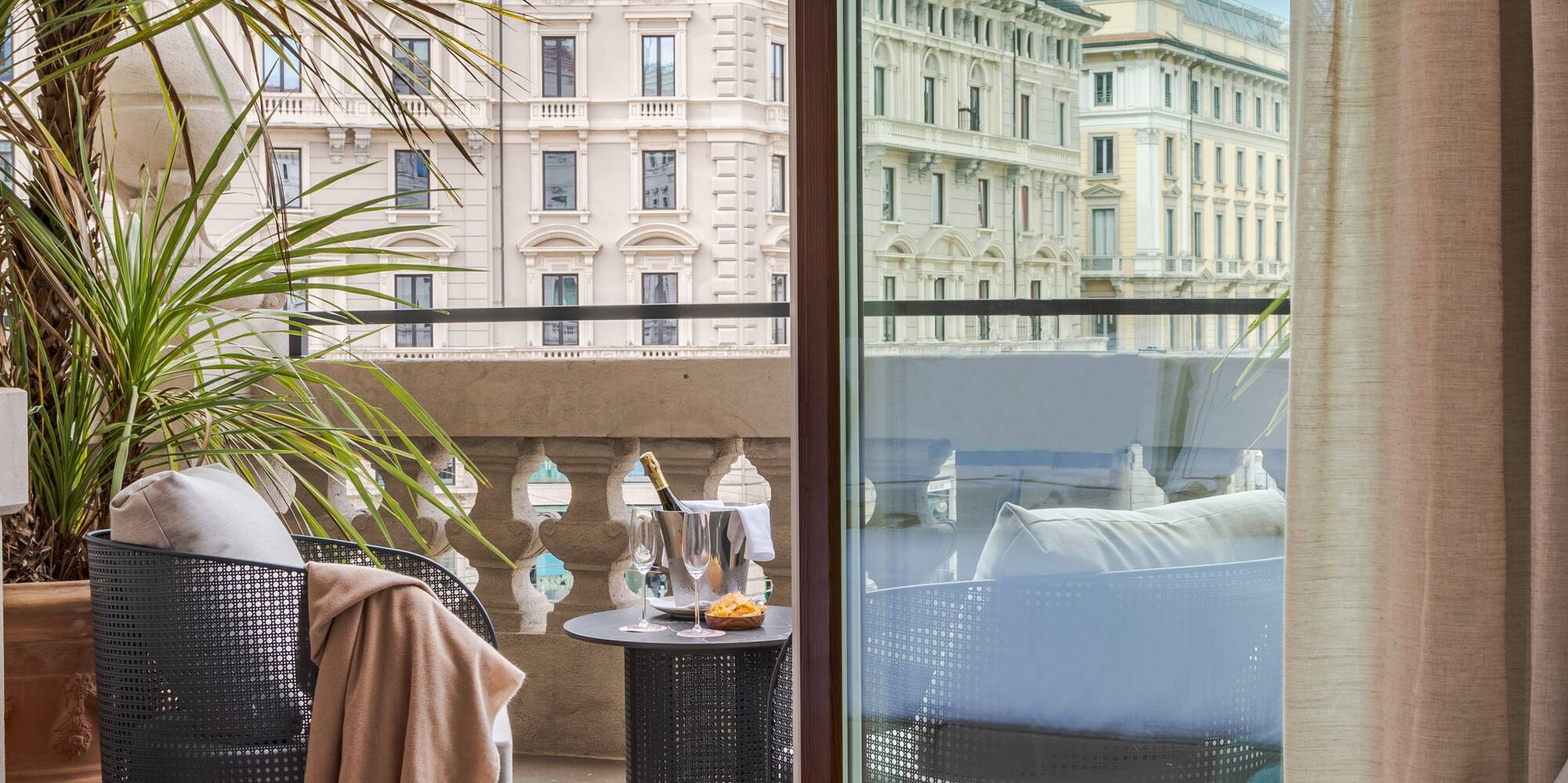 a room with a glass door and a balcony with a plant and a window
