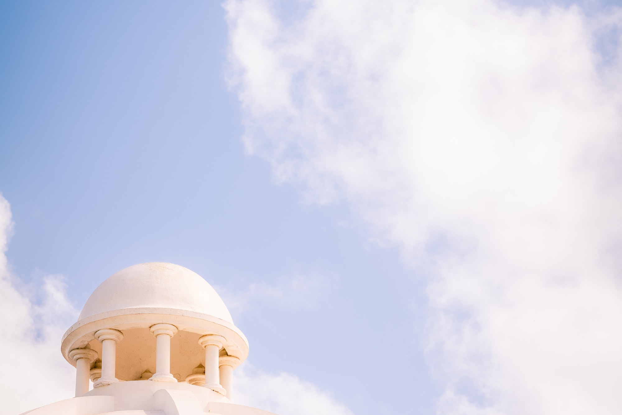 a white dome with a blue sky and clouds