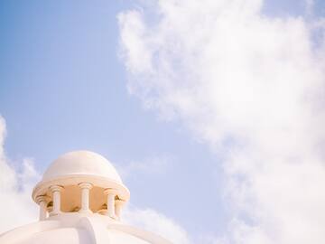 a white dome with a blue sky and clouds