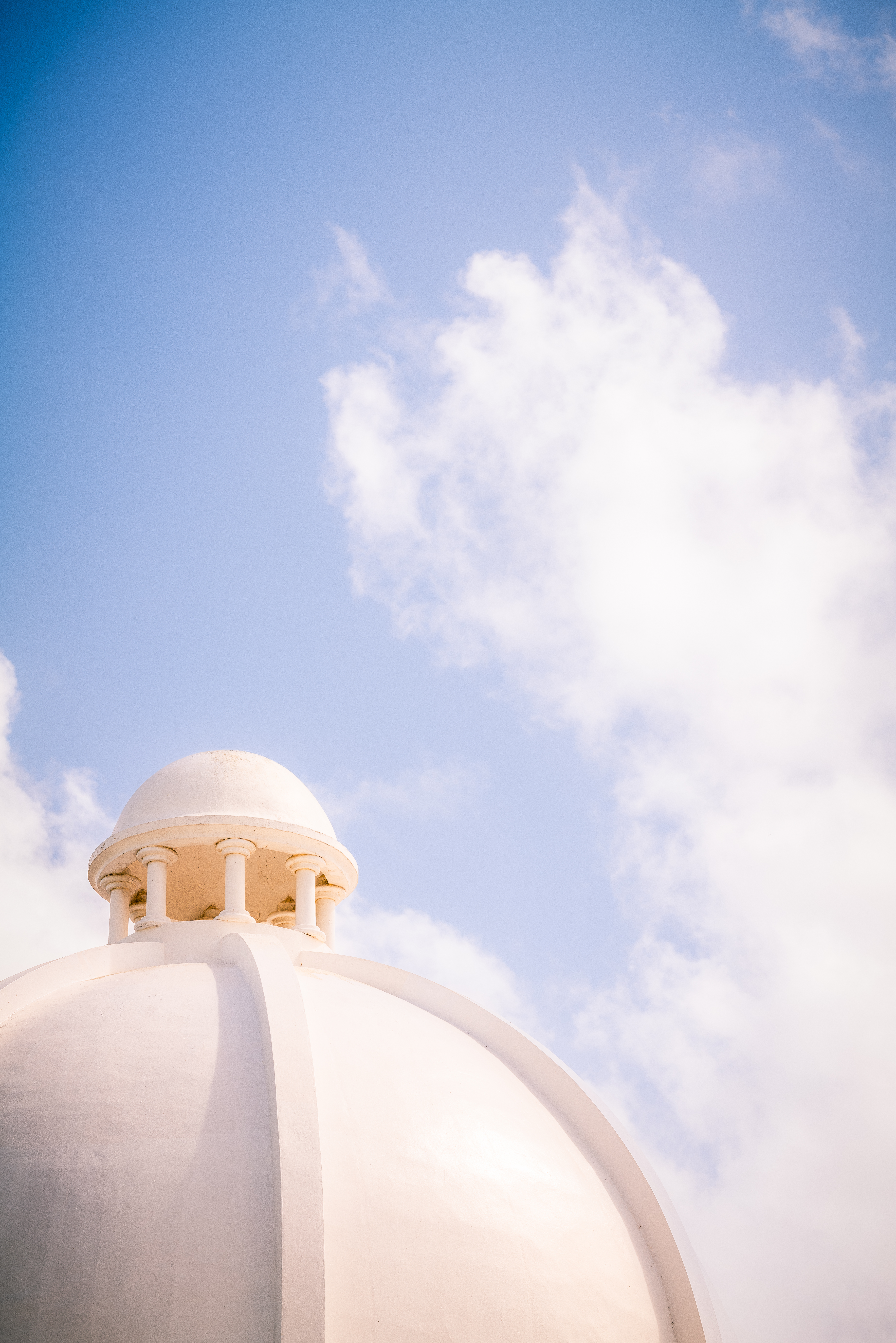 a white dome with a blue sky and clouds