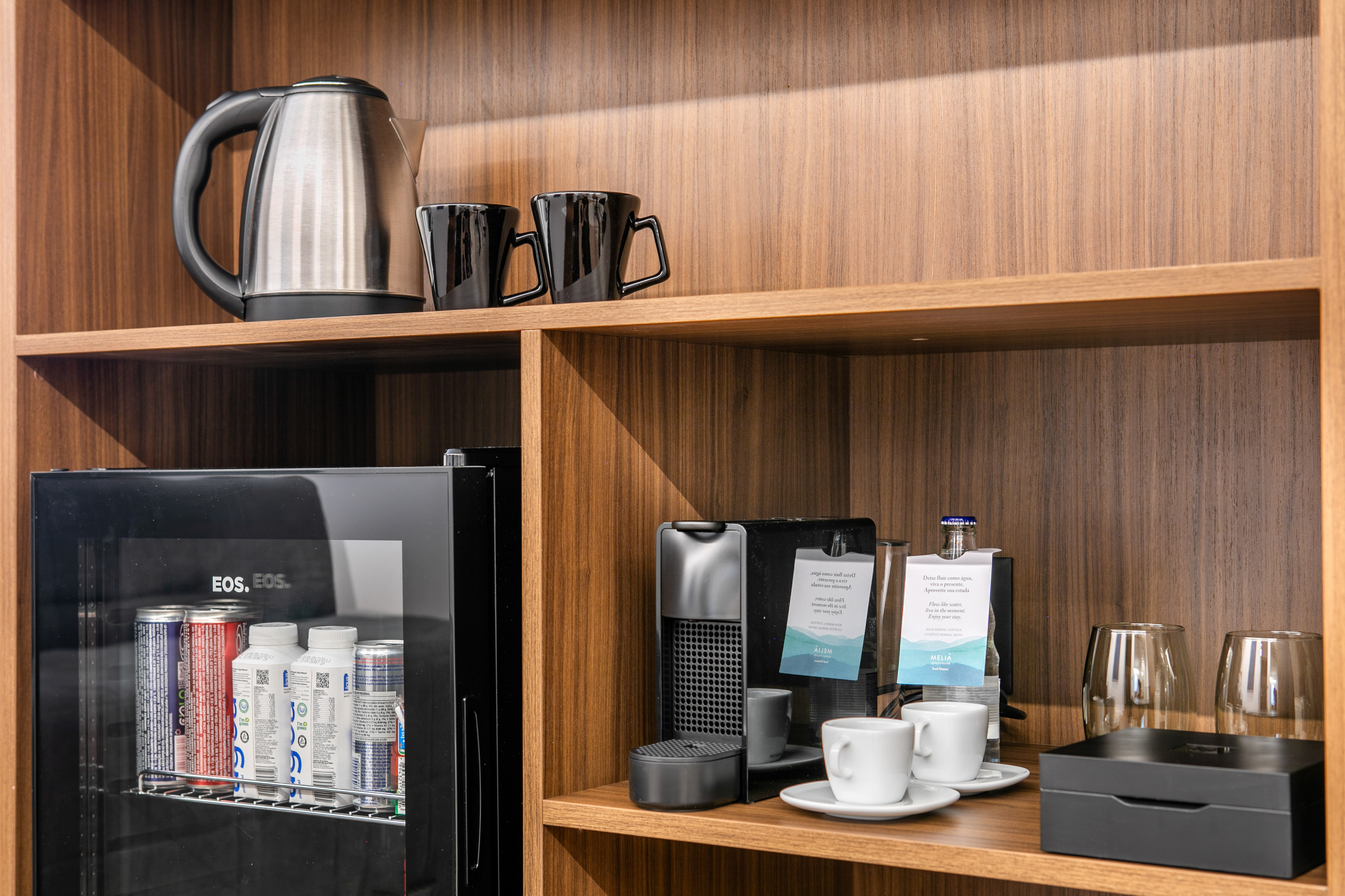 Hotel minibar with Nespresso machine, electric kettle, and stocked mini-fridge.