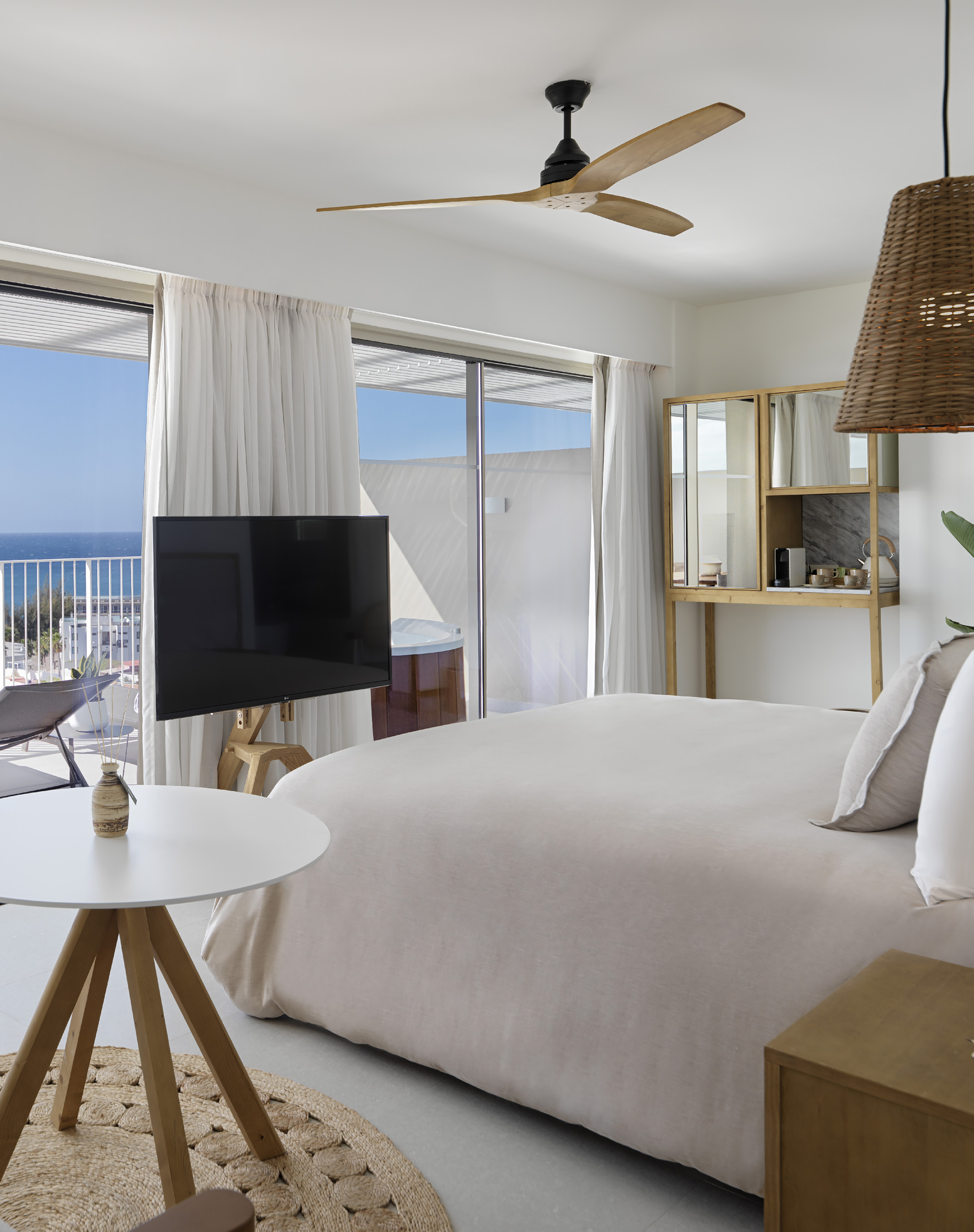 Ocean view bedroom with balcony, hot tub, large bed, and minimalist design.