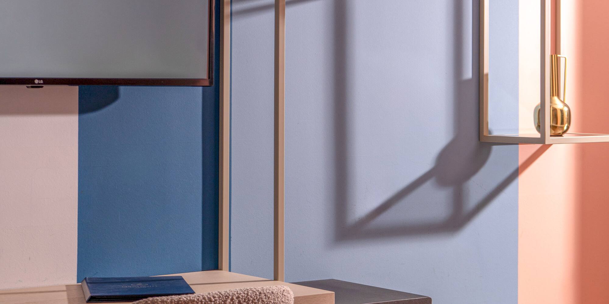Modern hotel room interior: desk, TV, open wardrobe with hangers, and safe.