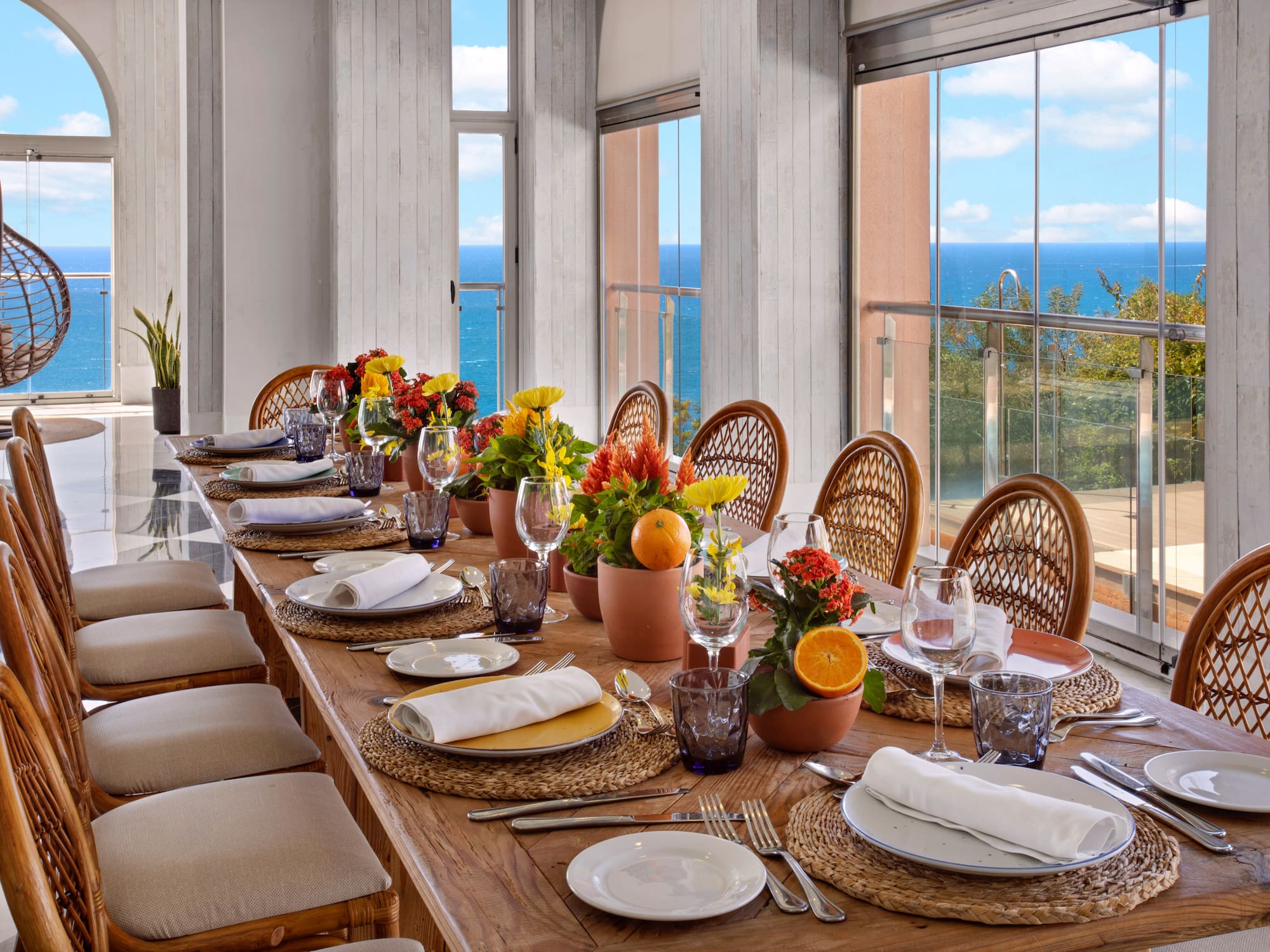 Luxury dining table, flowers, wicker chairs, panoramic ocean view.