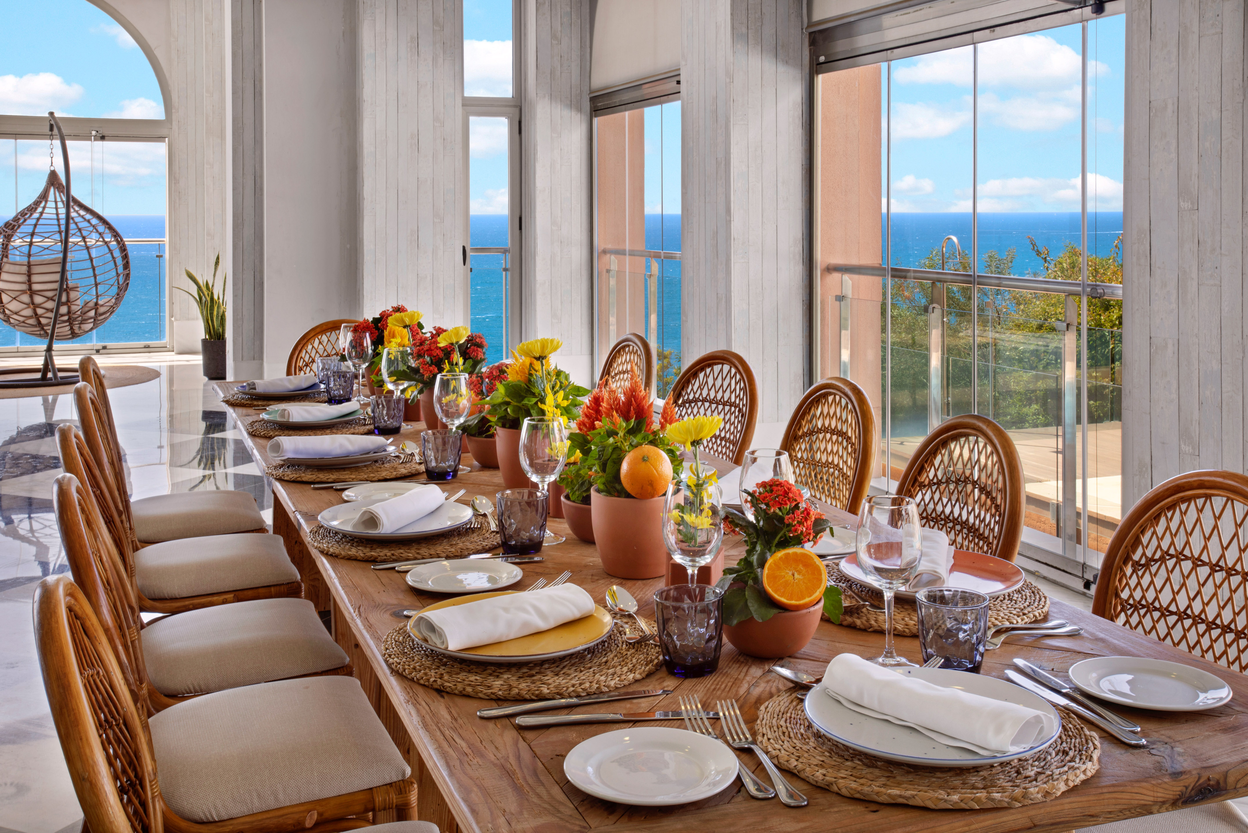 Luxury dining table, flowers, wicker chairs, panoramic ocean view.