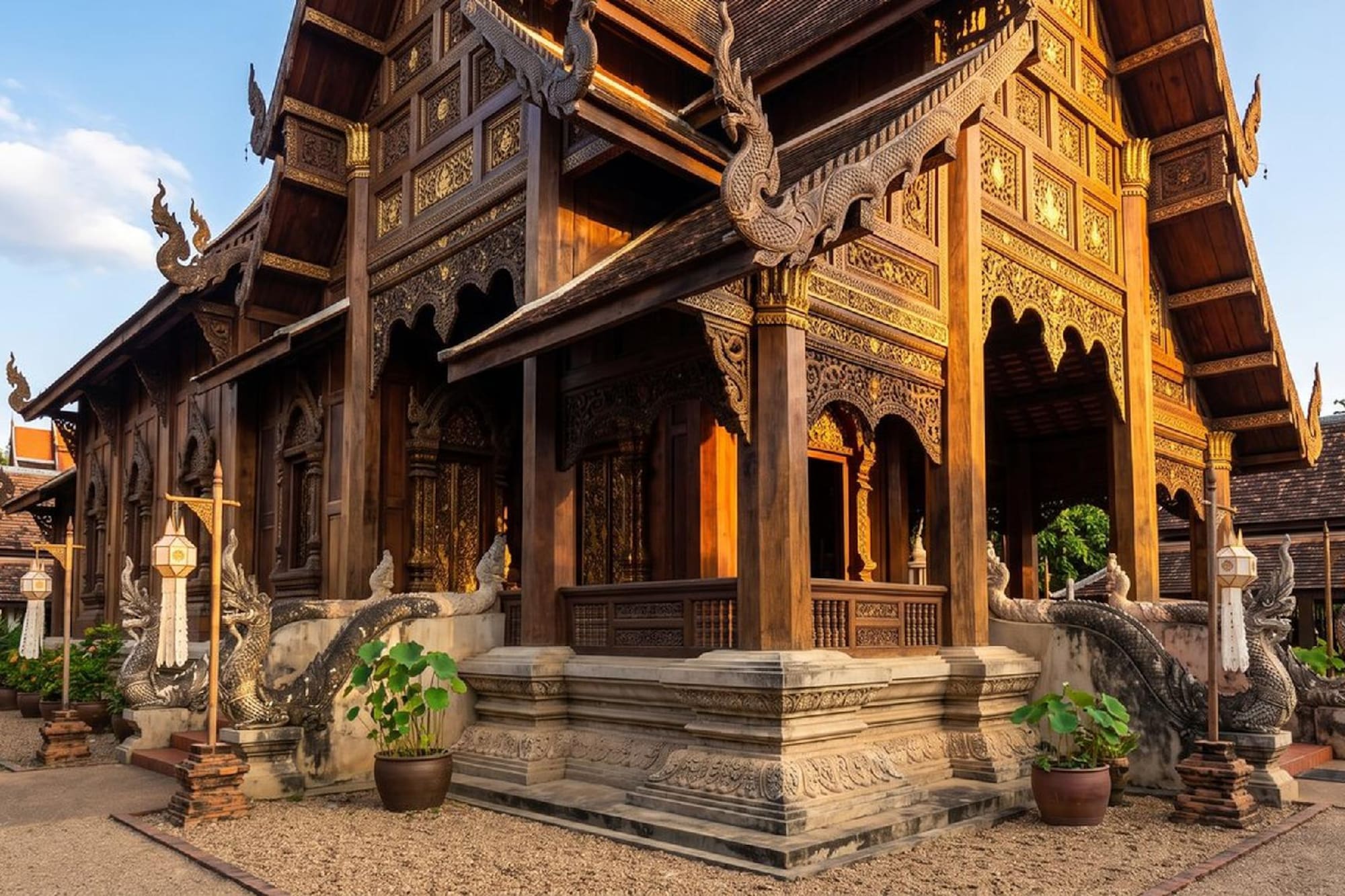 Traditional Thai wooden temple with ornate carvings and naga statues.