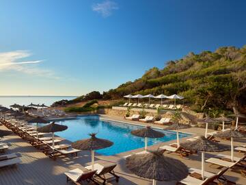 a pool with umbrellas and chairs on a beach