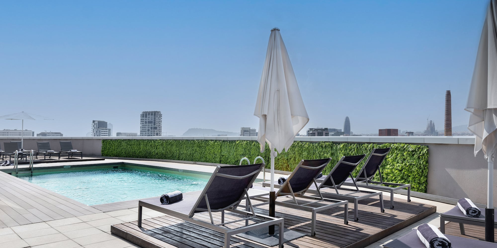 a pool with chairs and umbrella on a rooftop