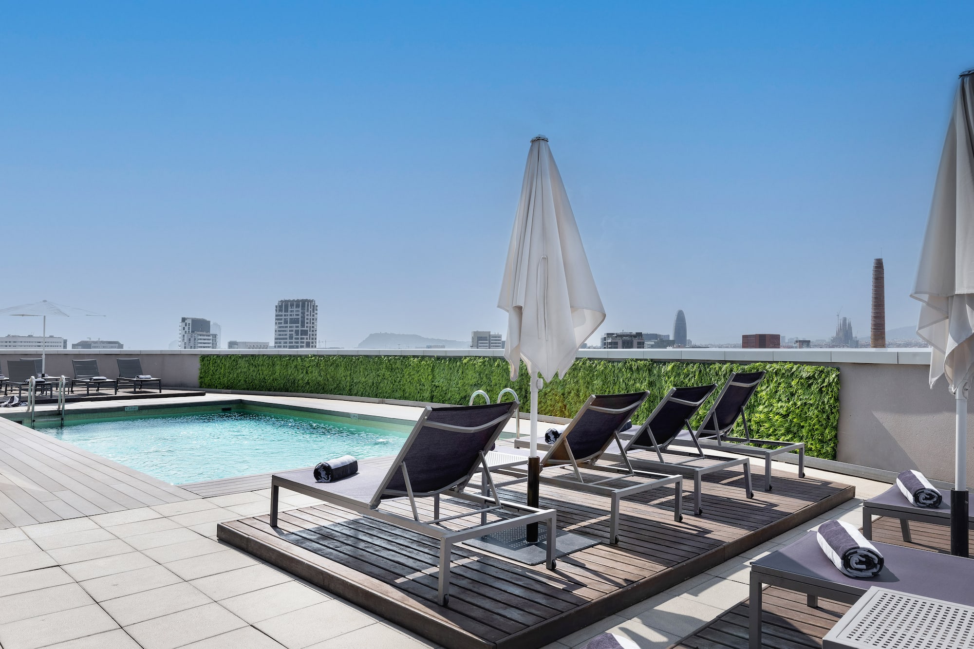a pool with chairs and umbrella on a rooftop