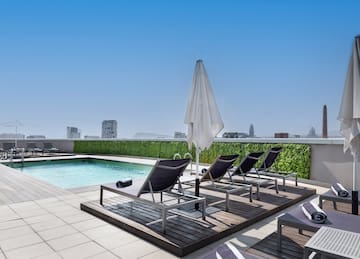 a pool with chairs and umbrella on a rooftop