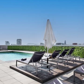 a pool with chairs and umbrella on a rooftop