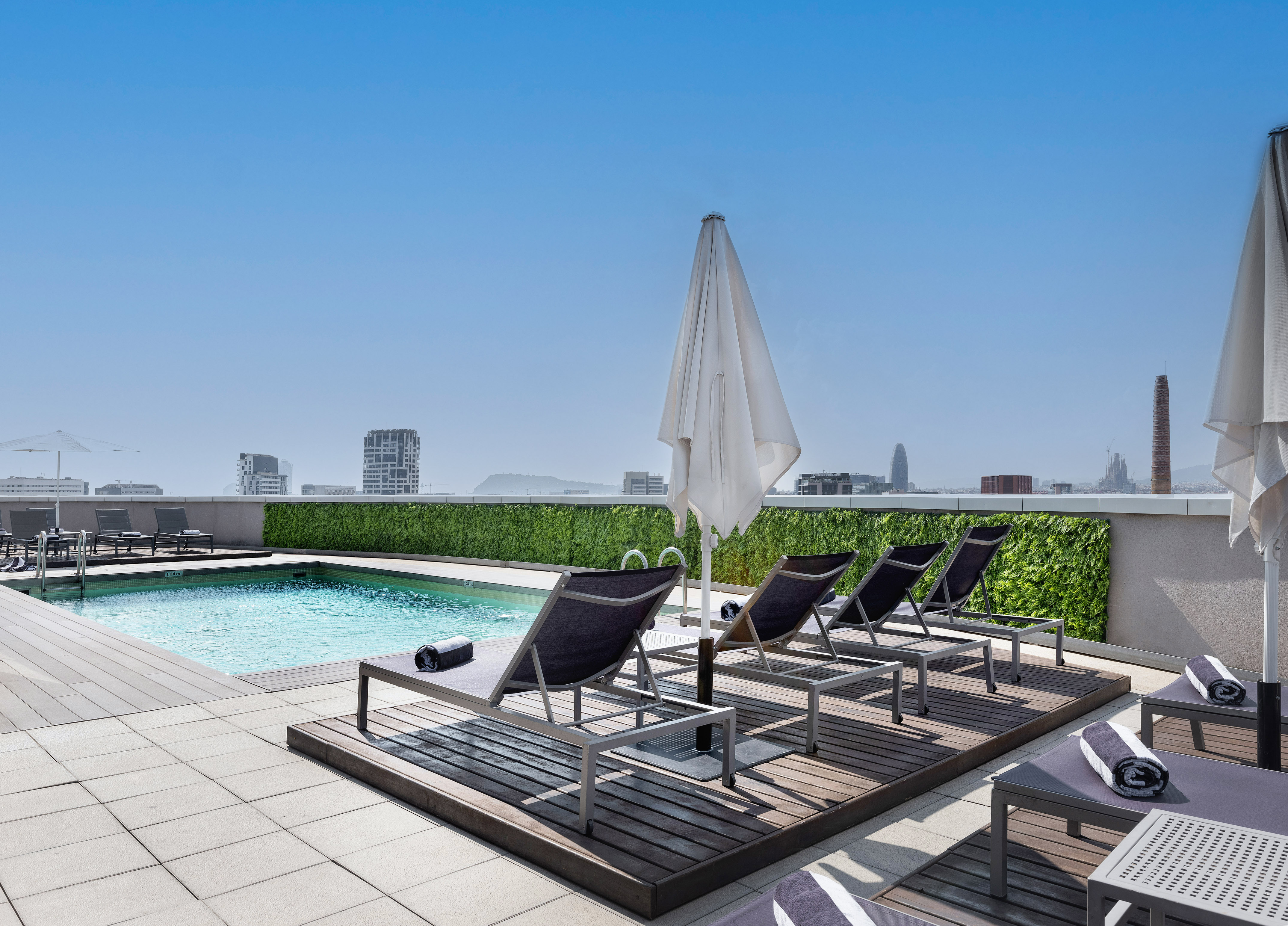 a pool with chairs and umbrella on a rooftop