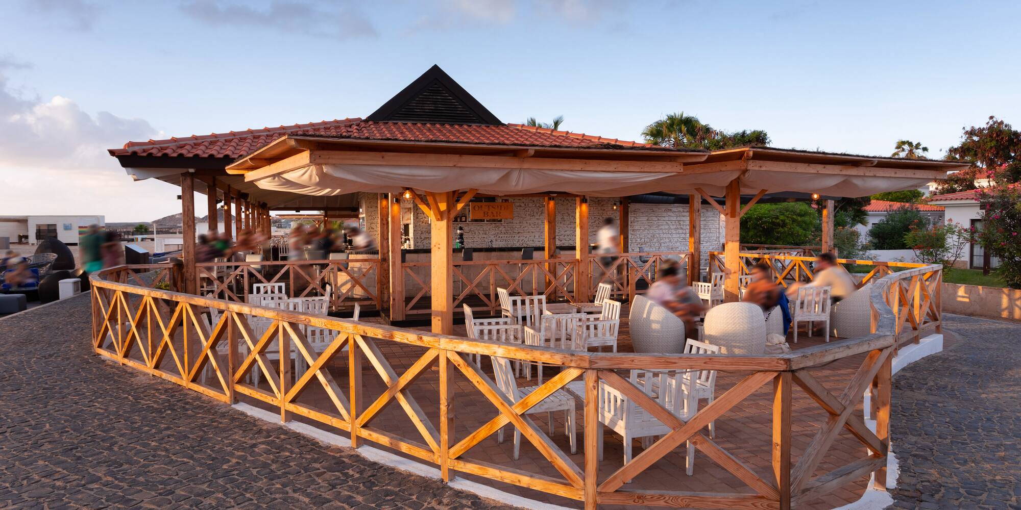 a group of people sitting at tables outside a restaurant