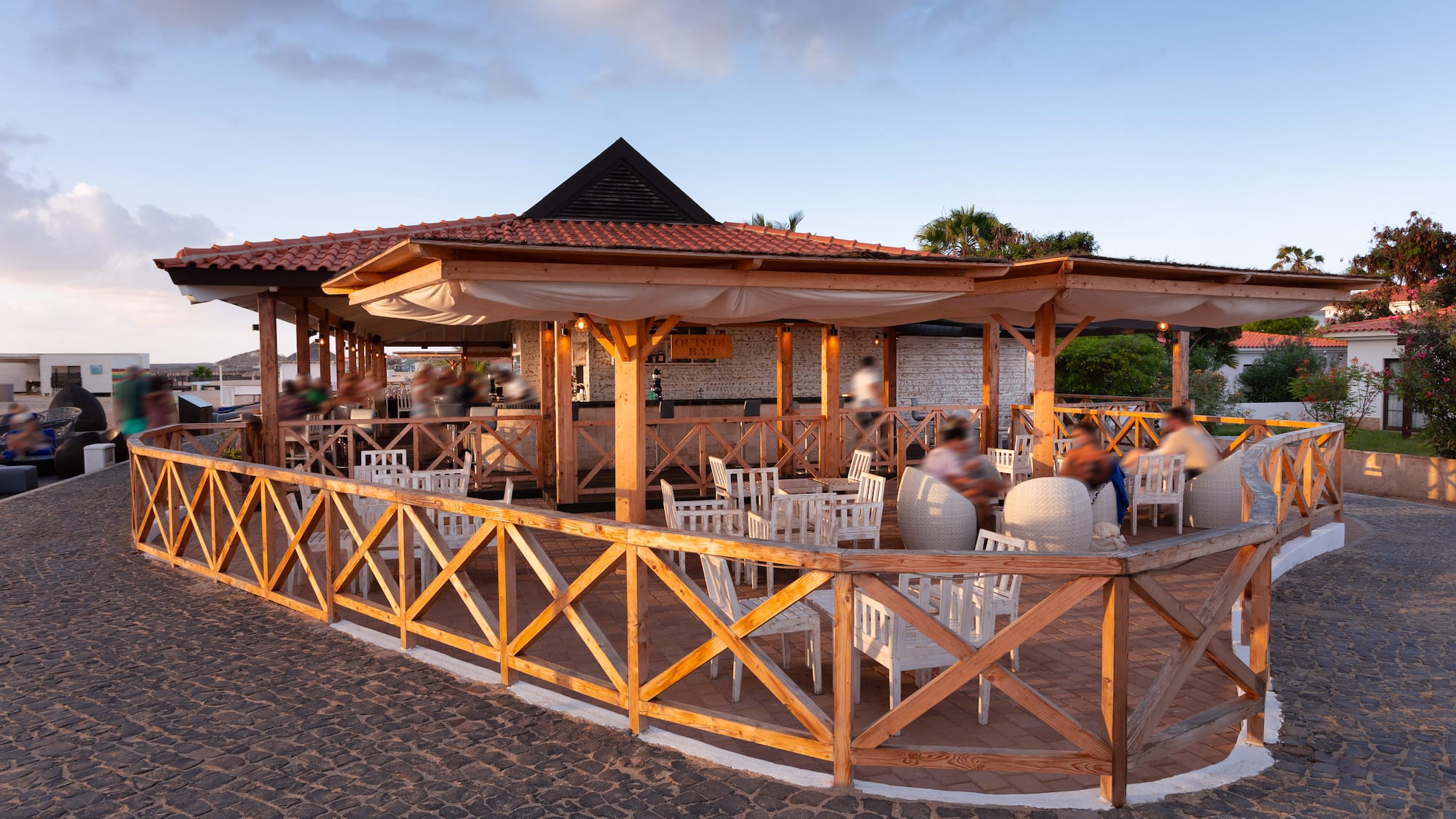 a group of people sitting at tables outside a restaurant