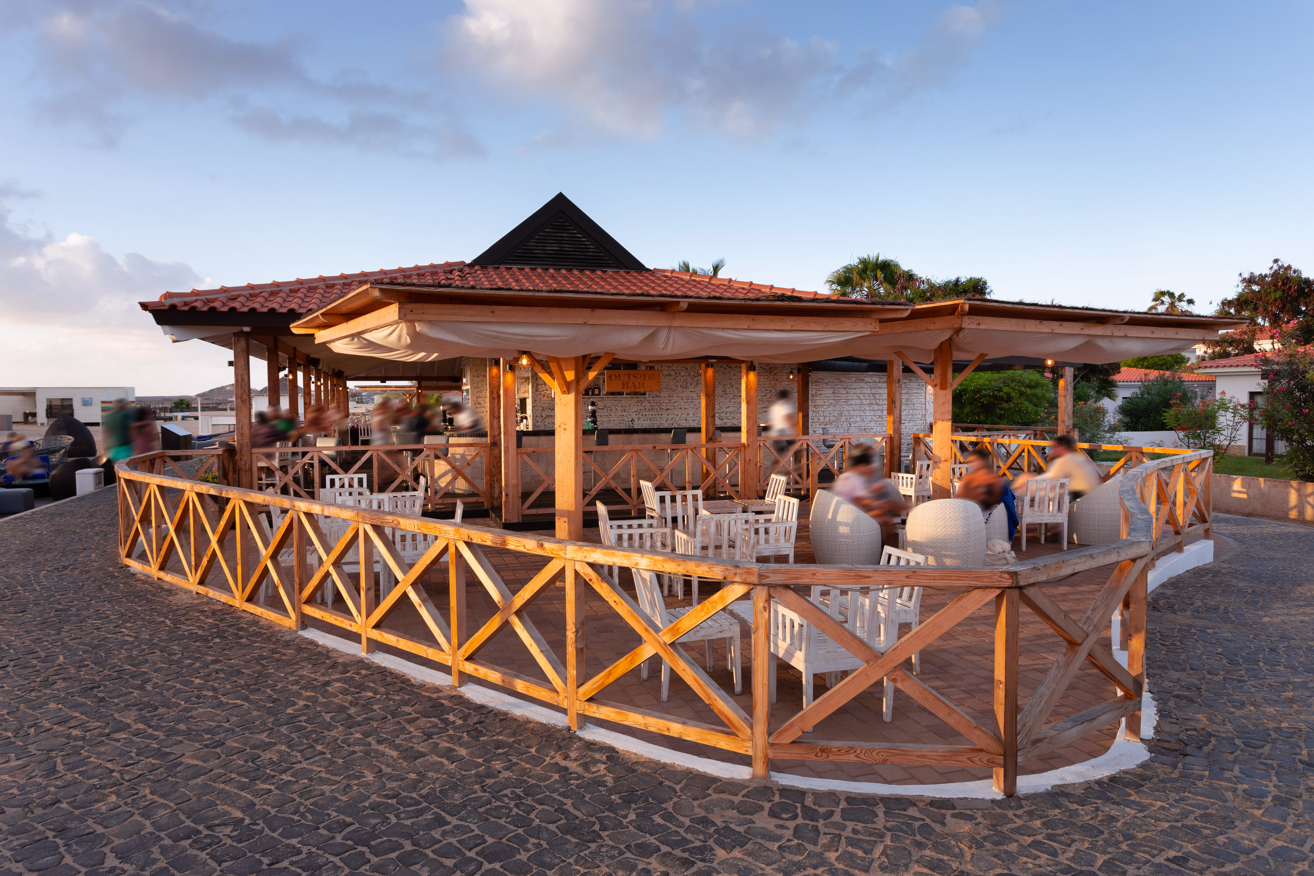 a group of people sitting at tables outside a restaurant