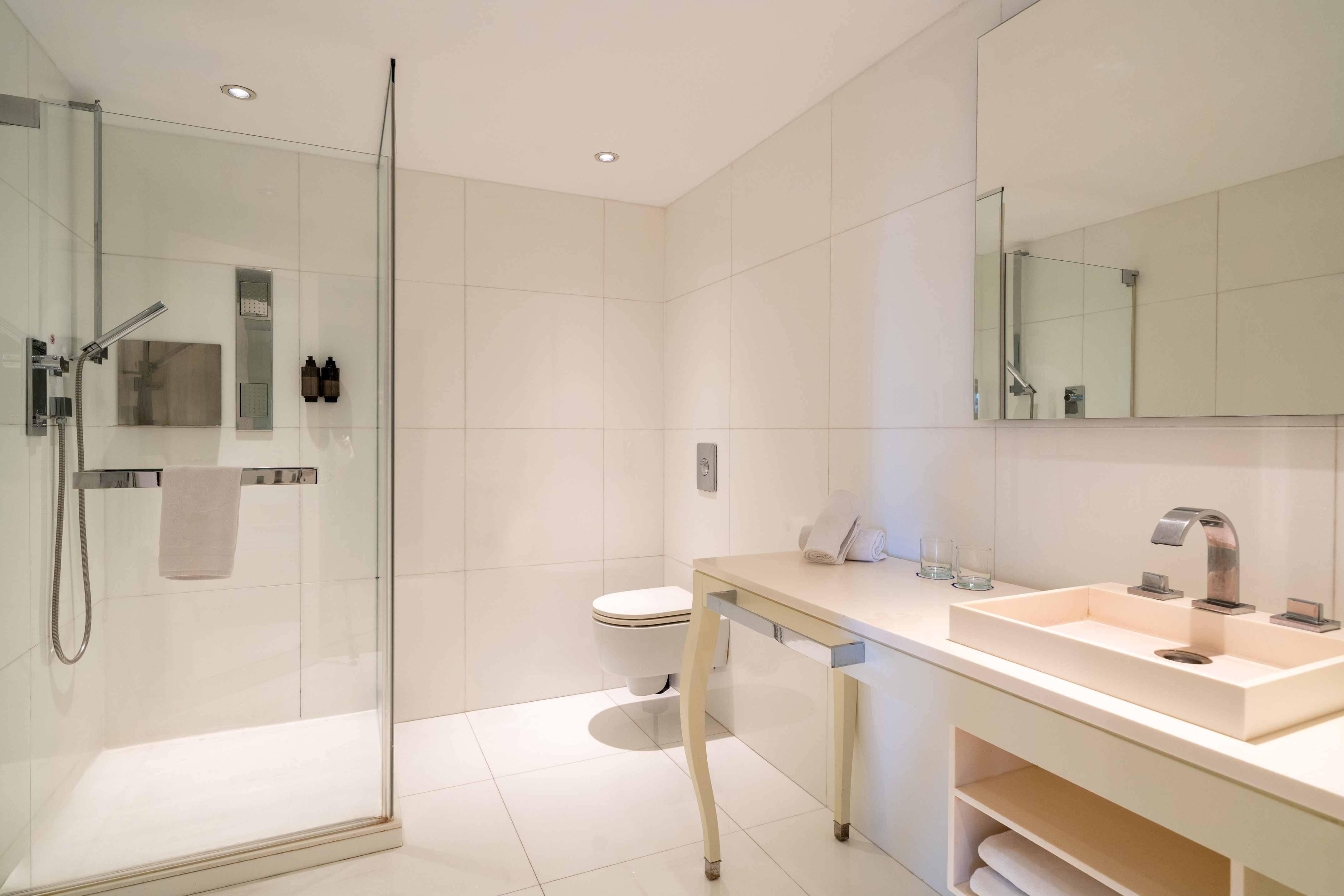 Modern minimalist bathroom with glass shower, toilet, and vanity sink.