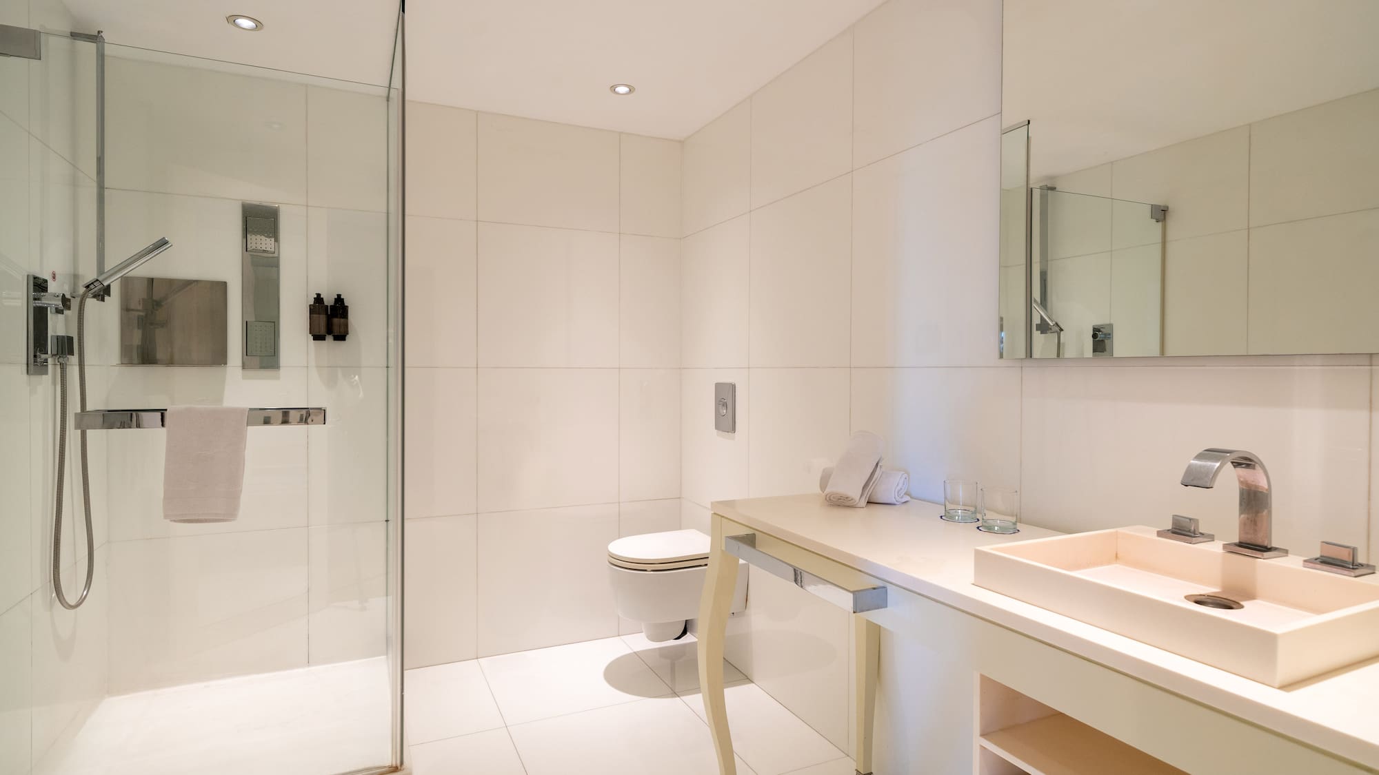 Modern minimalist bathroom with glass shower, toilet, and vanity sink.