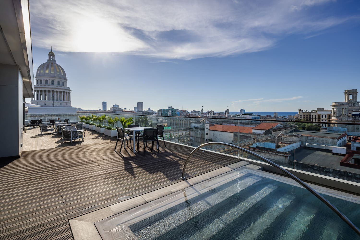 a rooftop with a pool and chairs and a large building with a dome roof