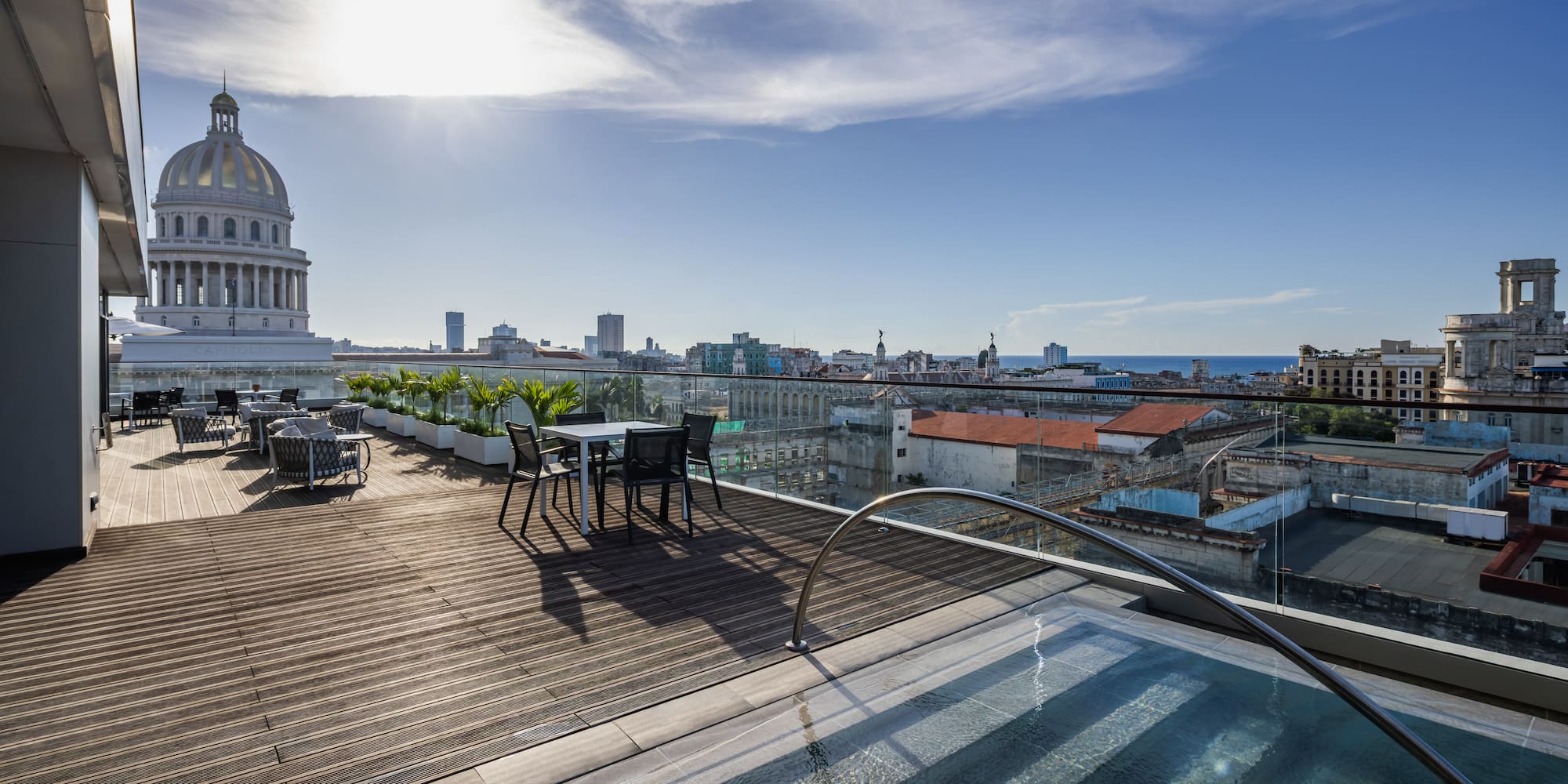 a rooftop with a pool and chairs and a large building with a dome roof