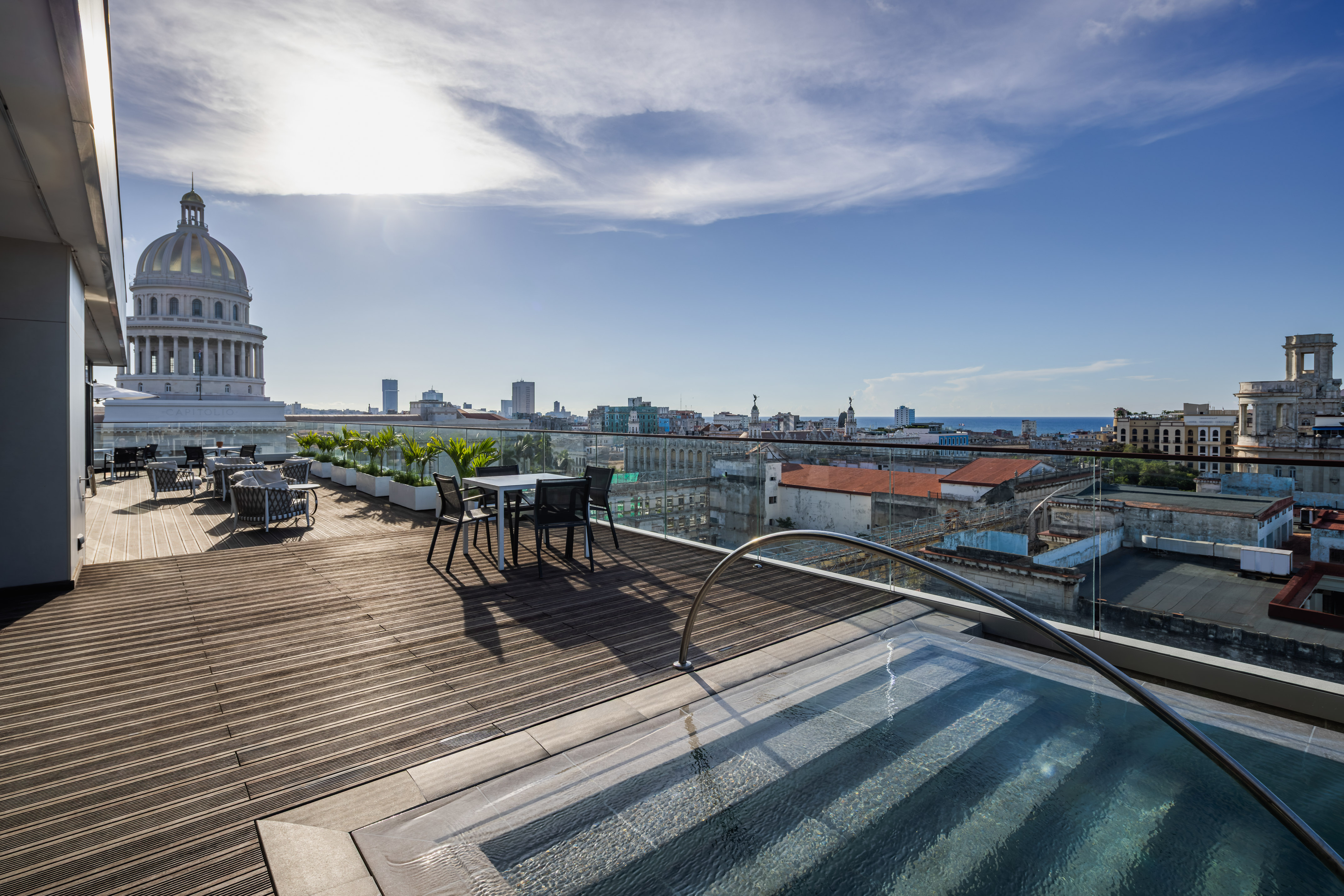a rooftop with a pool and chairs and a large building with a dome roof