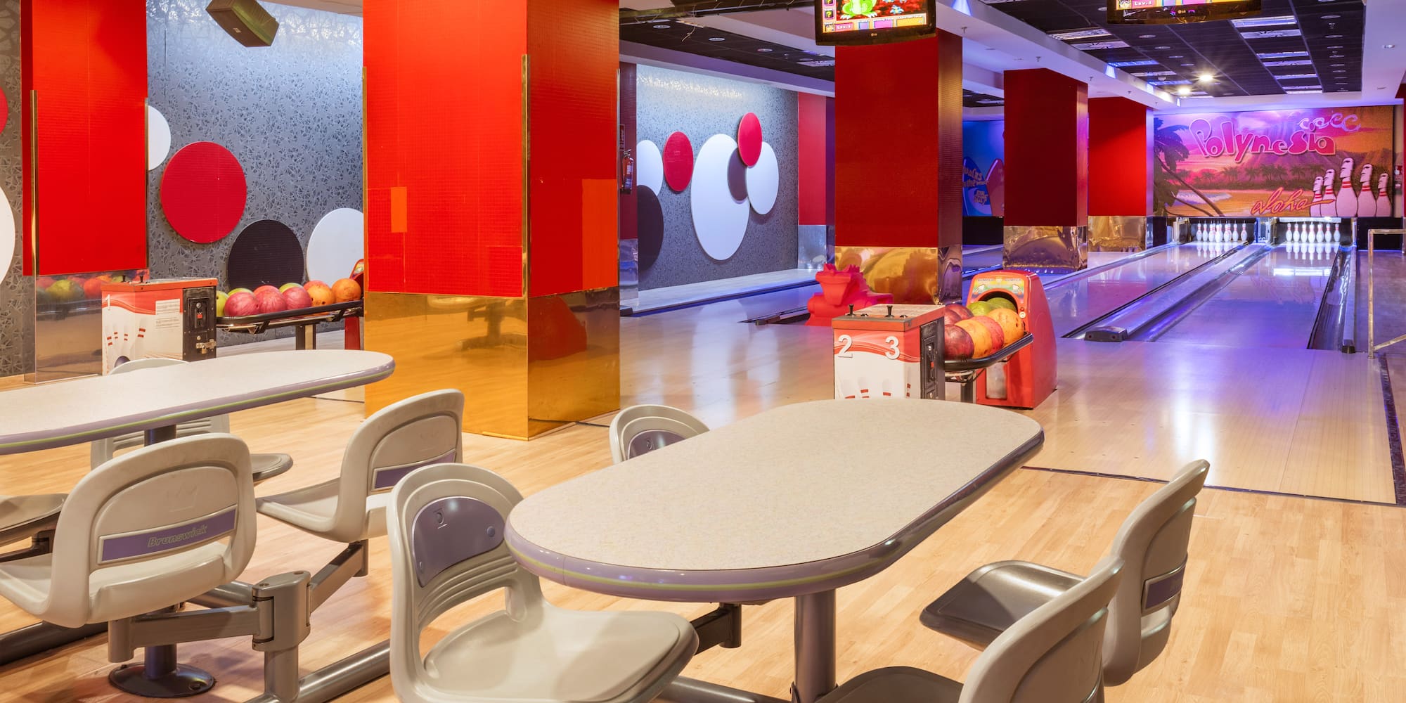 Modern bowling alley with multiple lanes, seating area, and vibrant decor.