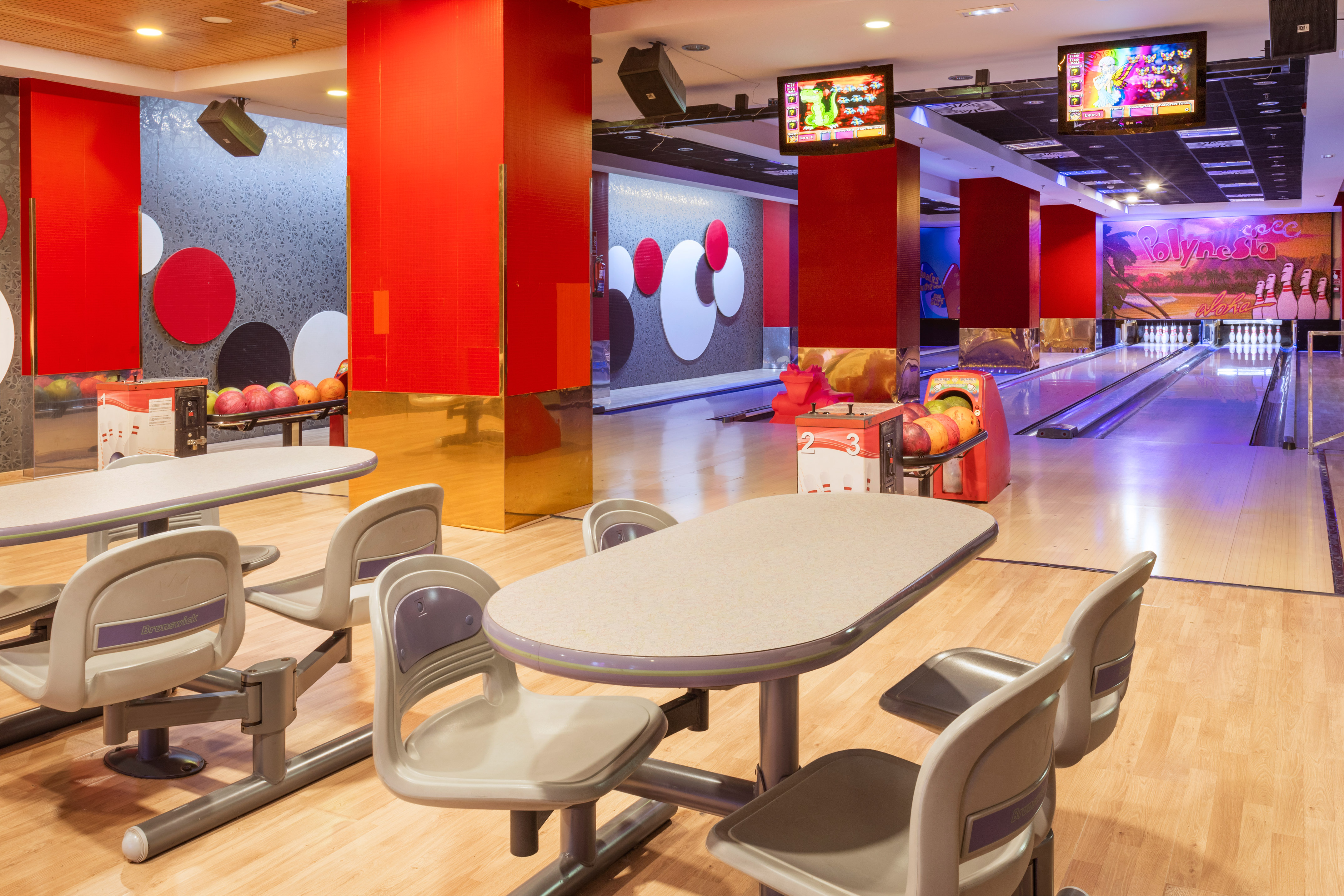 Modern bowling alley with multiple lanes, seating area, and vibrant decor.