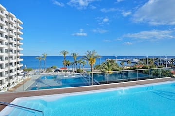 a pool with palm trees and a beach in the background