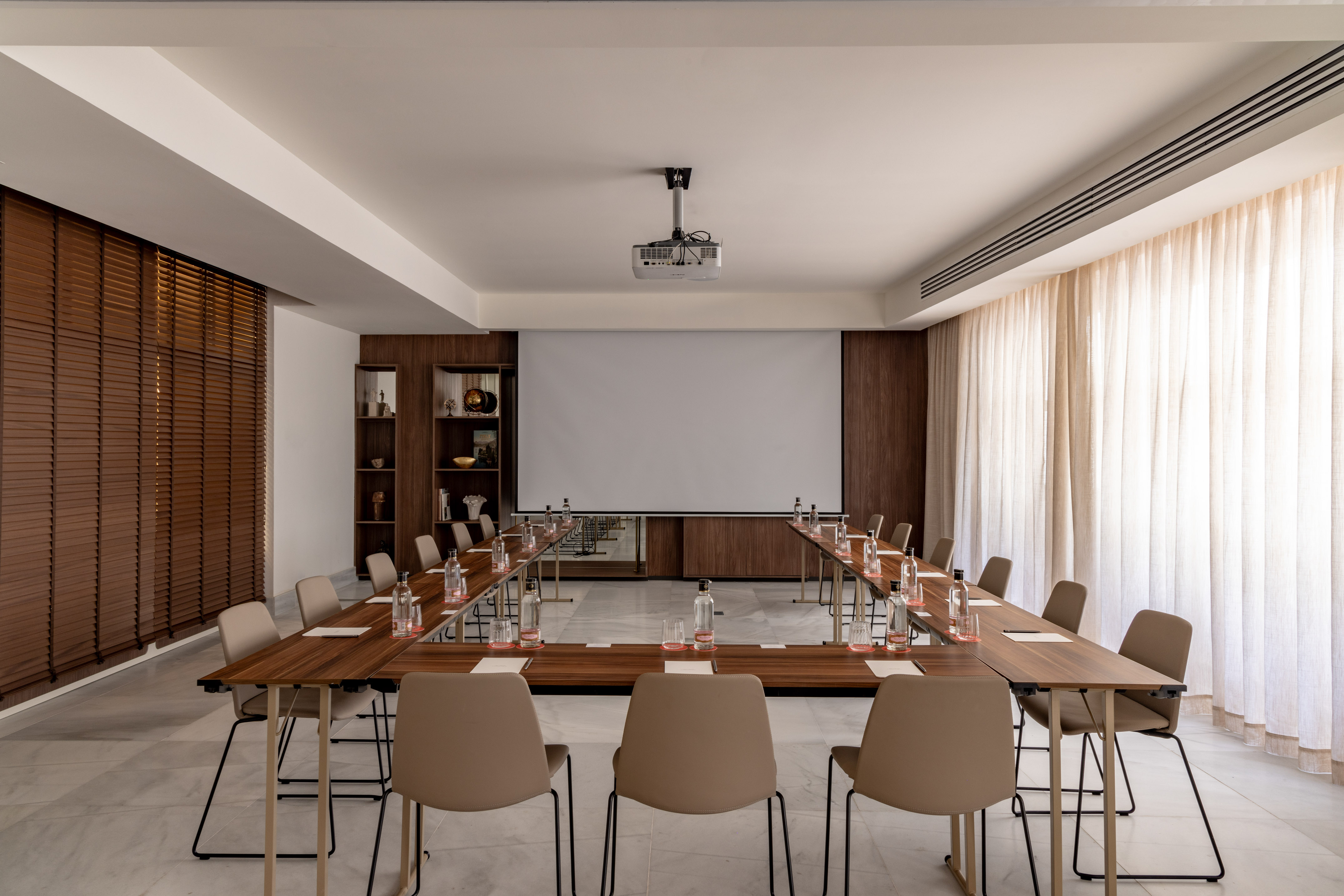Modern meeting room with U-shape table, projector, and presentation screen.
