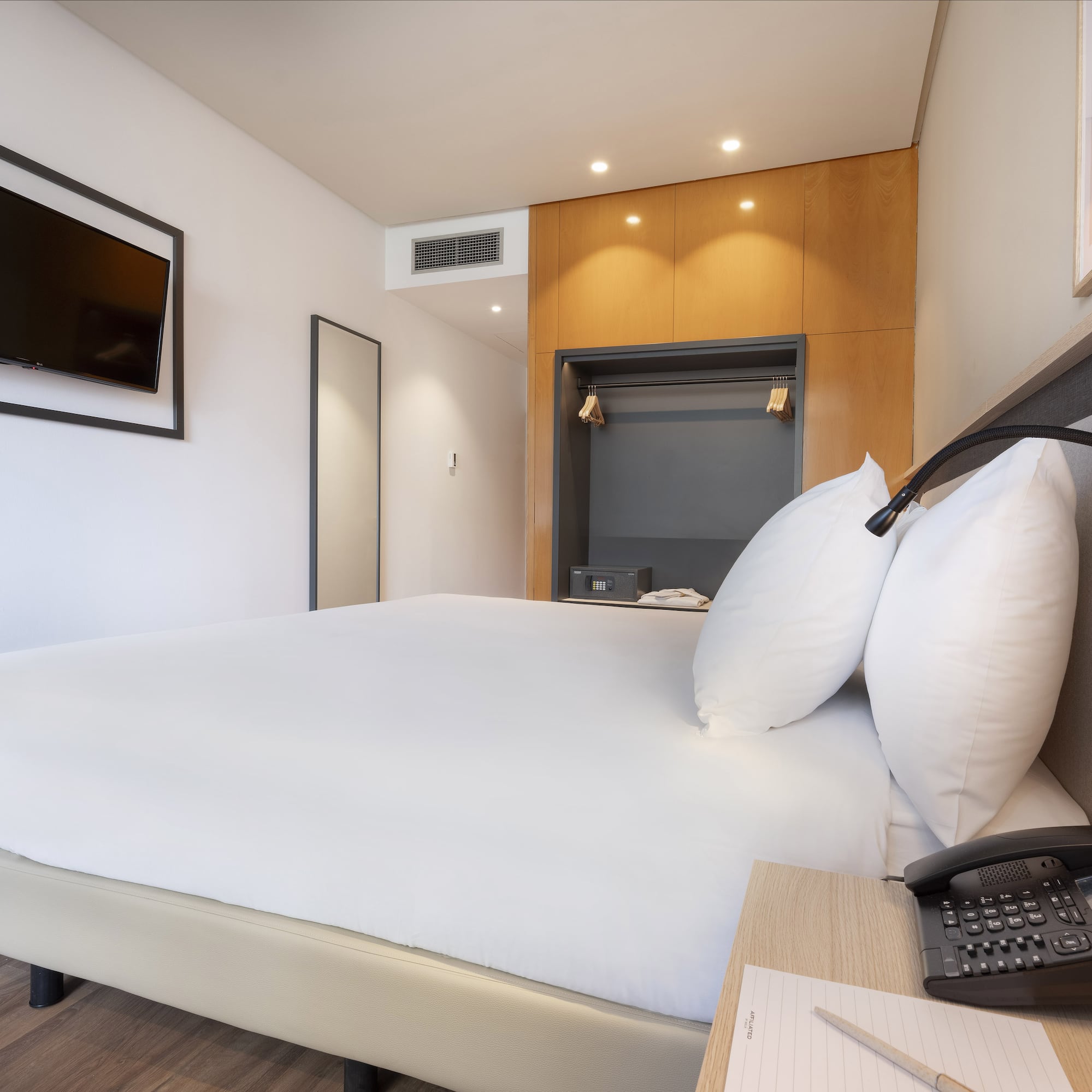 a bed with a telephone and a phone on a desk