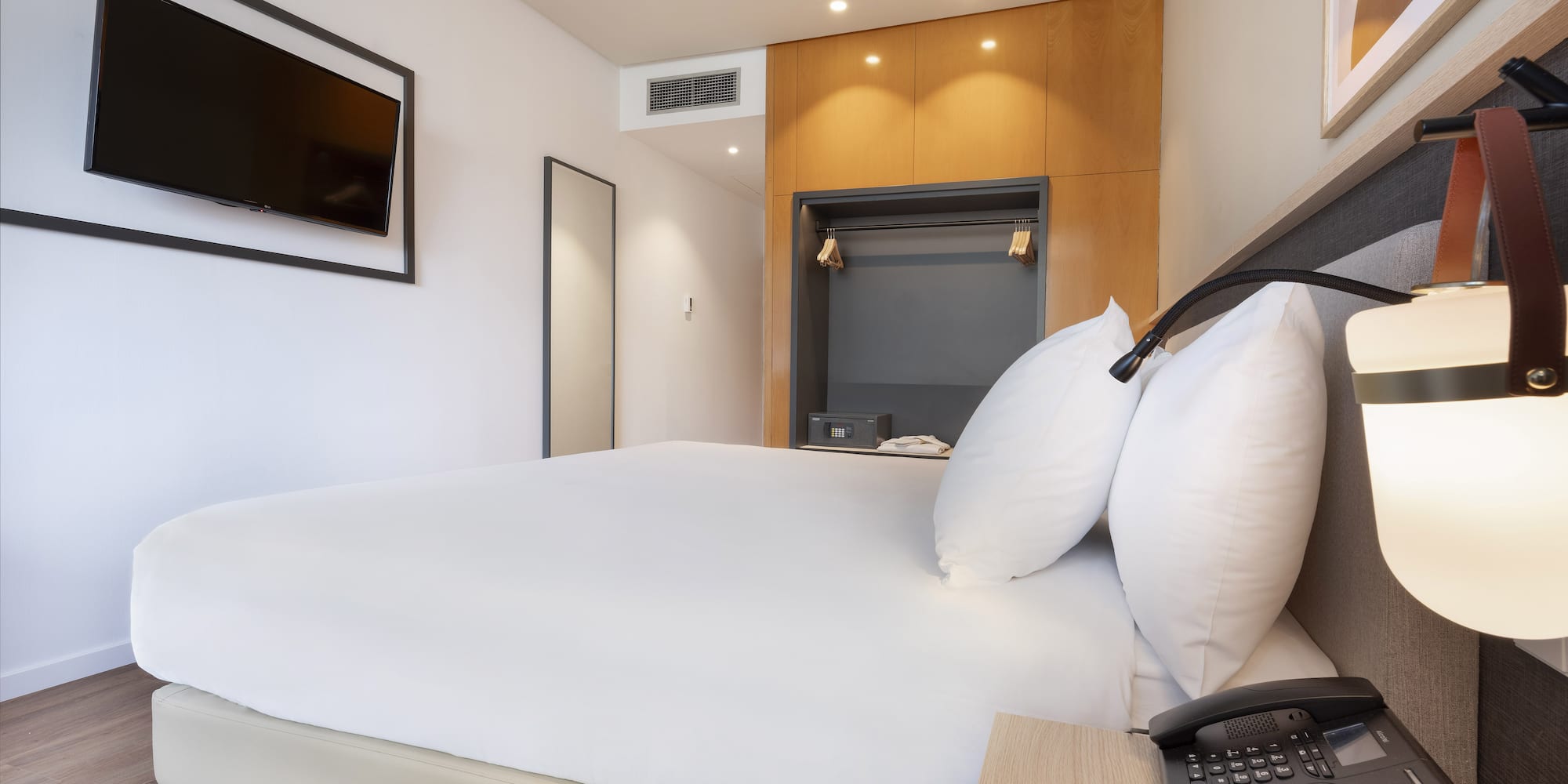 a bed with a telephone and a phone on a desk