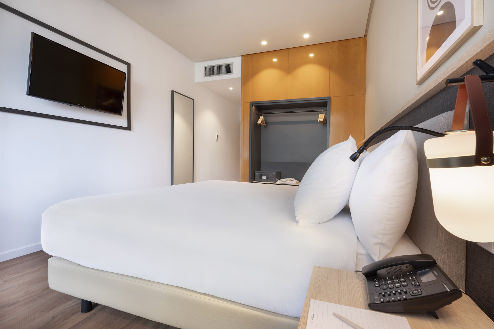 a bed with a telephone and a phone on a desk