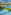 Resort with blue swimming pools, palm trees, thatched bar, and distant ocean.