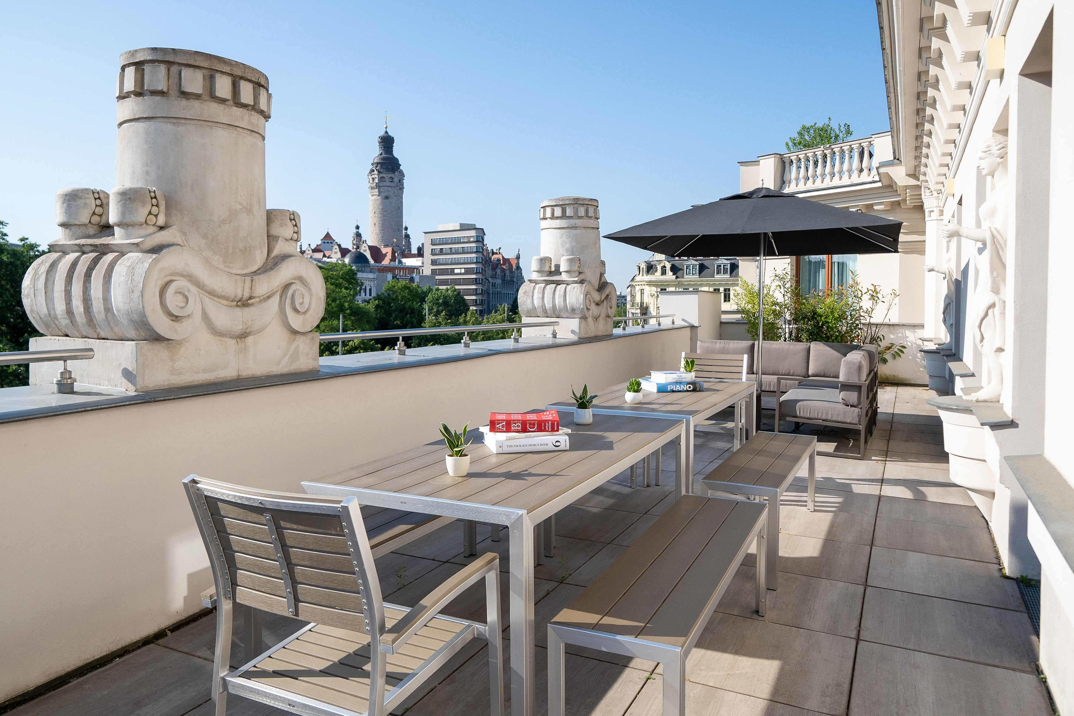 Modern rooftop terrace with dining and lounge furniture, city view of Leipzig.