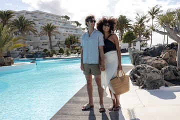 a man and woman holding hands by a pool