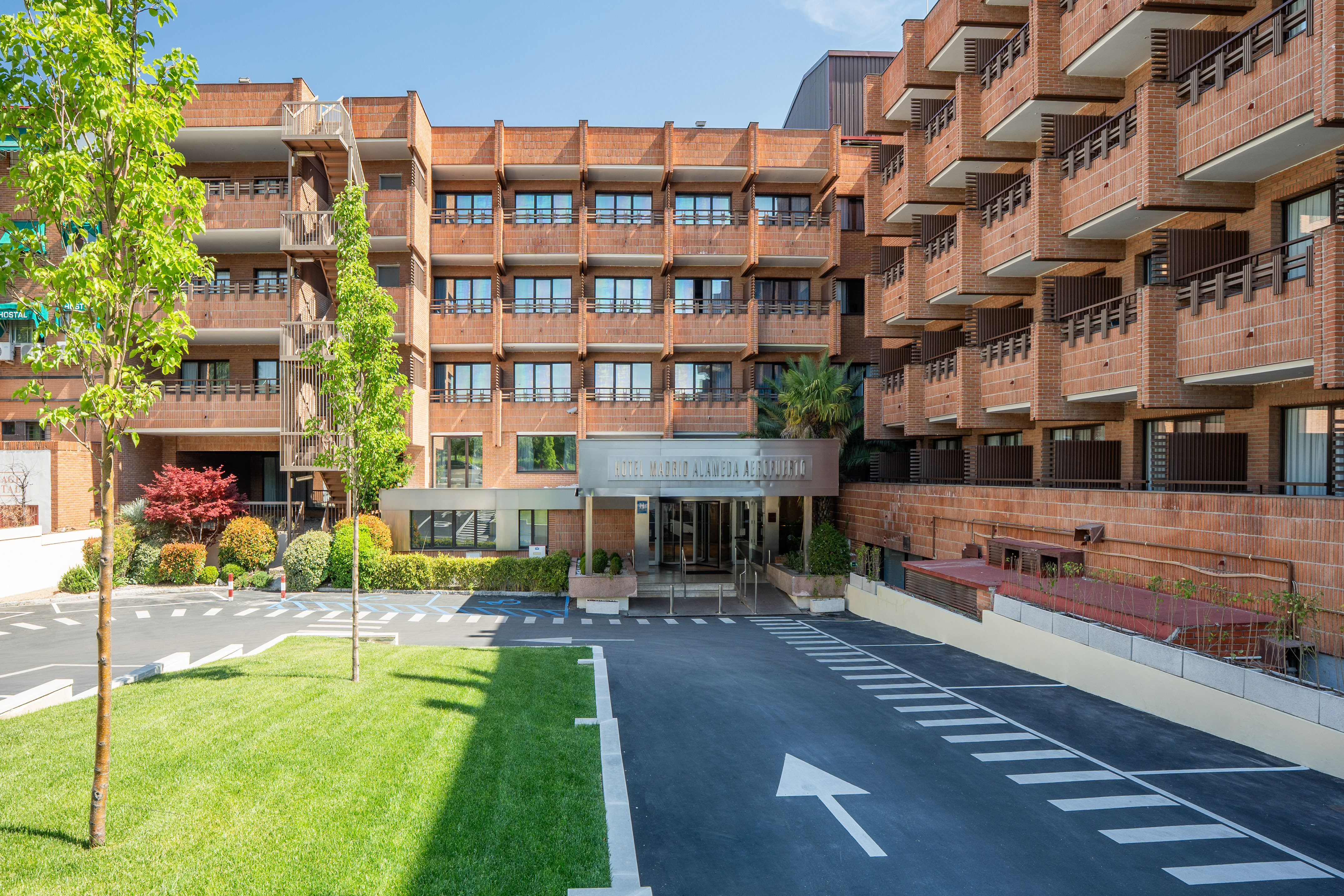 Hotel Madrid Alameda Aeropuerto: brick building, entrance, driveway, green lawn.