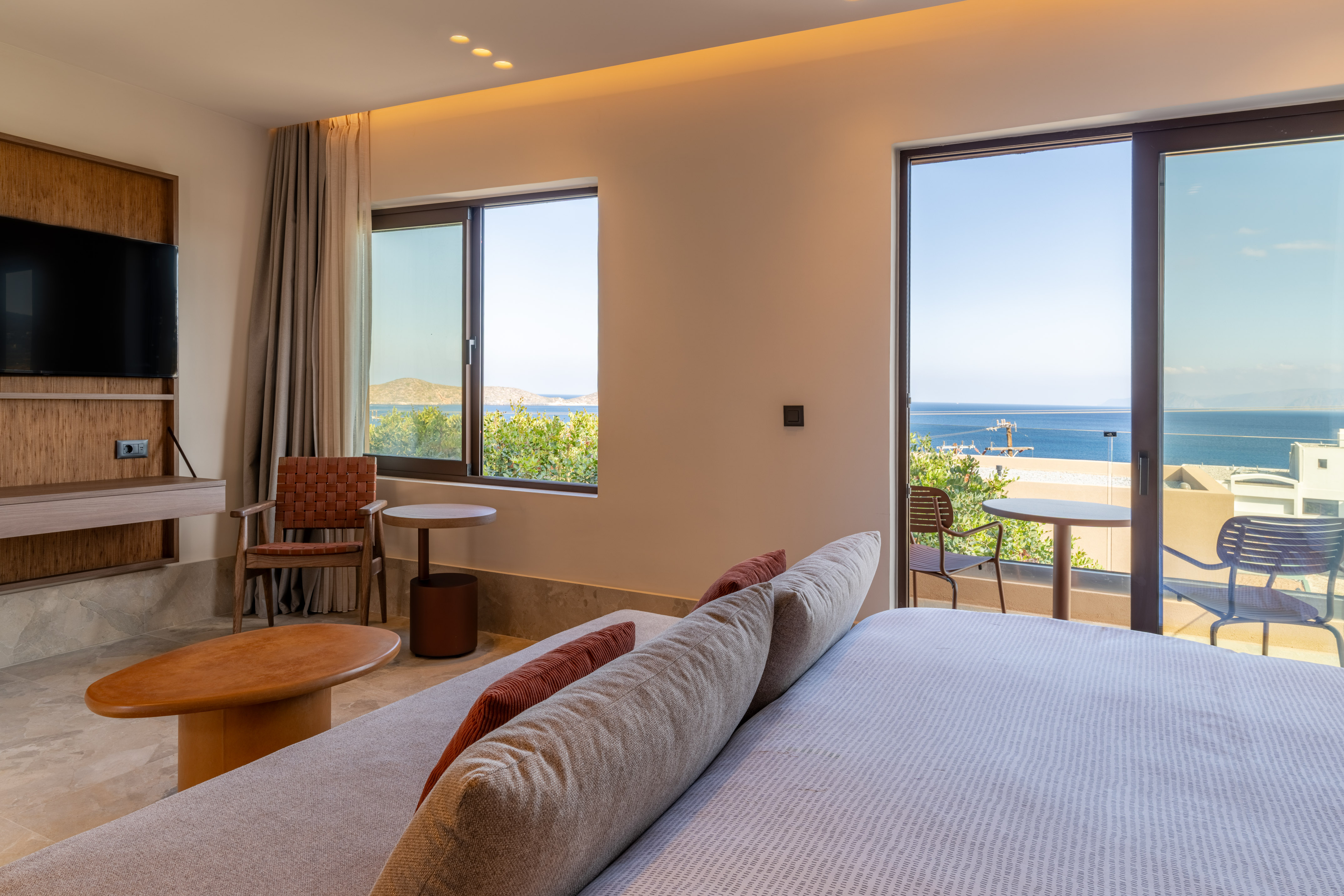 Modern hotel bedroom with balcony, ocean views, and king-size bed.